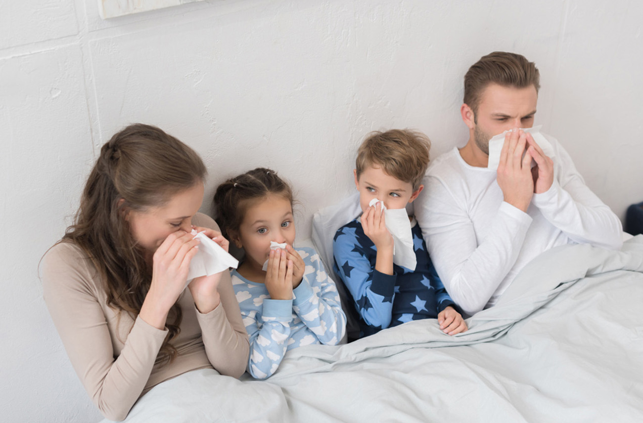 Sick family lying in a bed and blowing noses in napkins