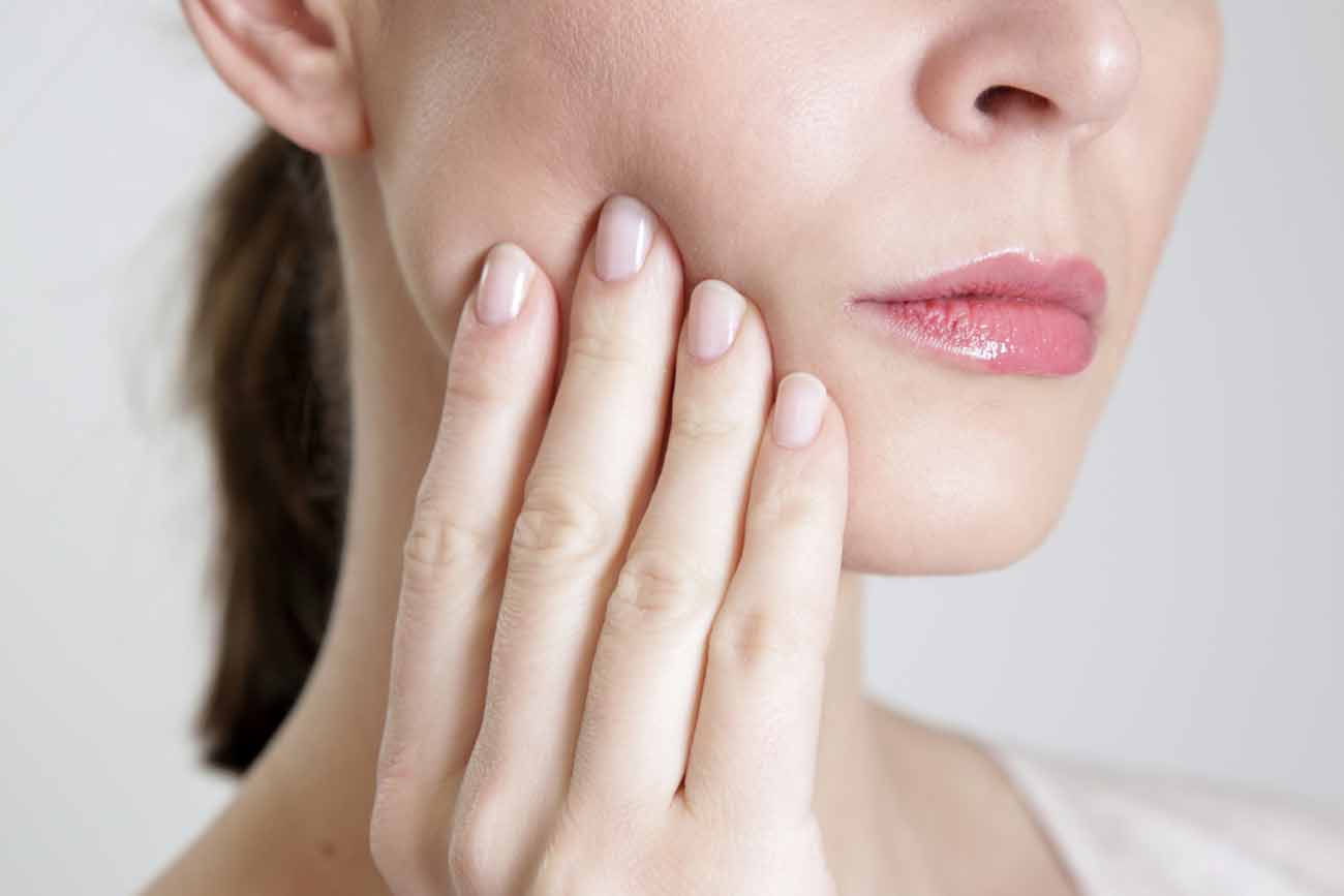 Studio shot of young woman with tooth pain, close up