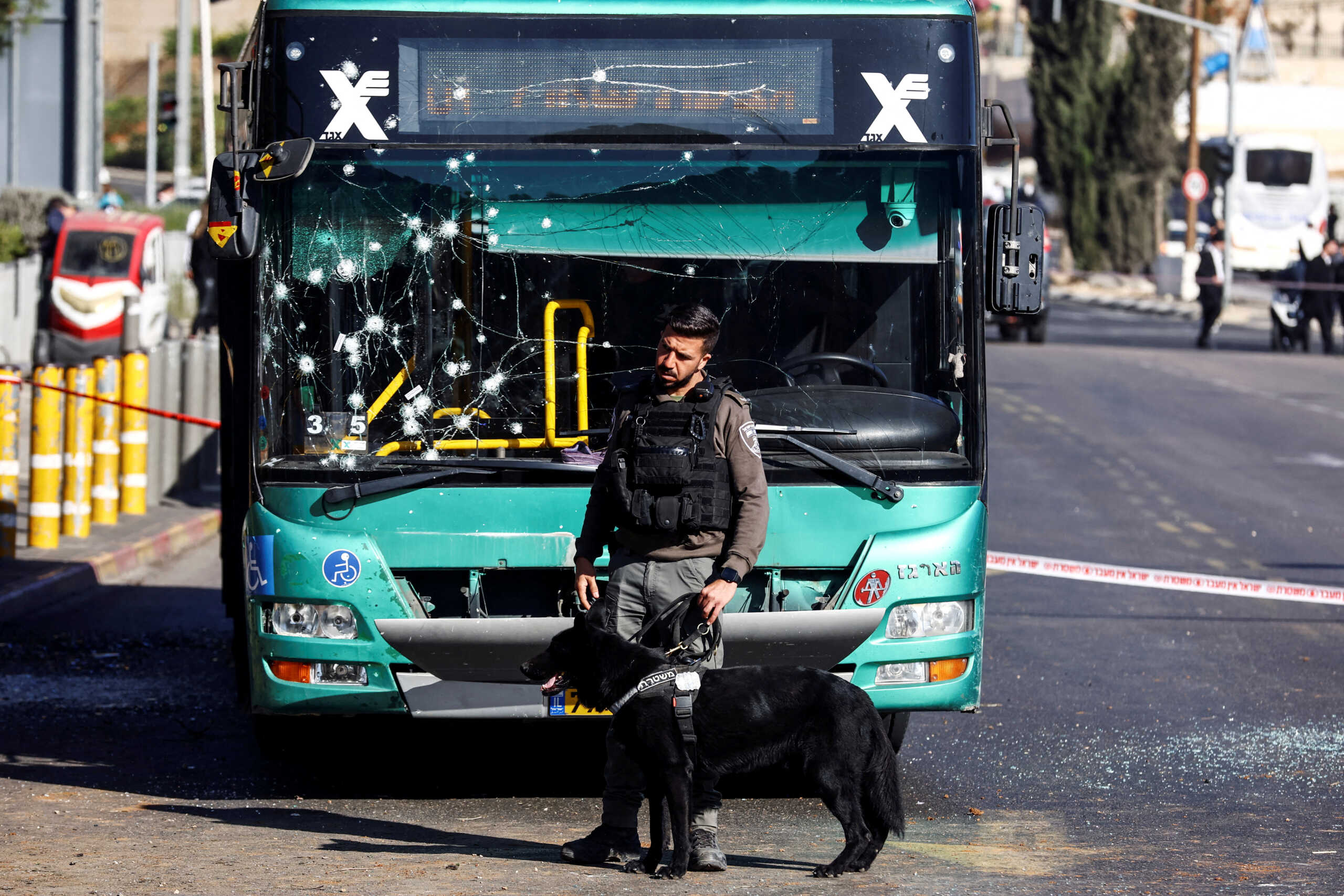 A police officer holds a service dog near a damaged bus after two explosions in Jerusalem November 23, 2022. REUTERS