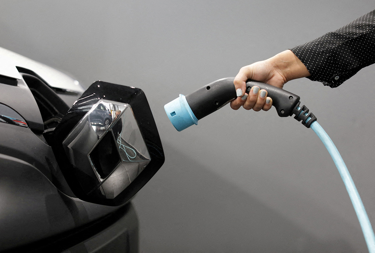 FILE PHOTO: A woman holds a cable to charge a Renault Kangoo ZE electric utility vehicle at a Renault automobile dealership in Cagnes-Sur-Mer, France, October 22, 2020. REUTERS