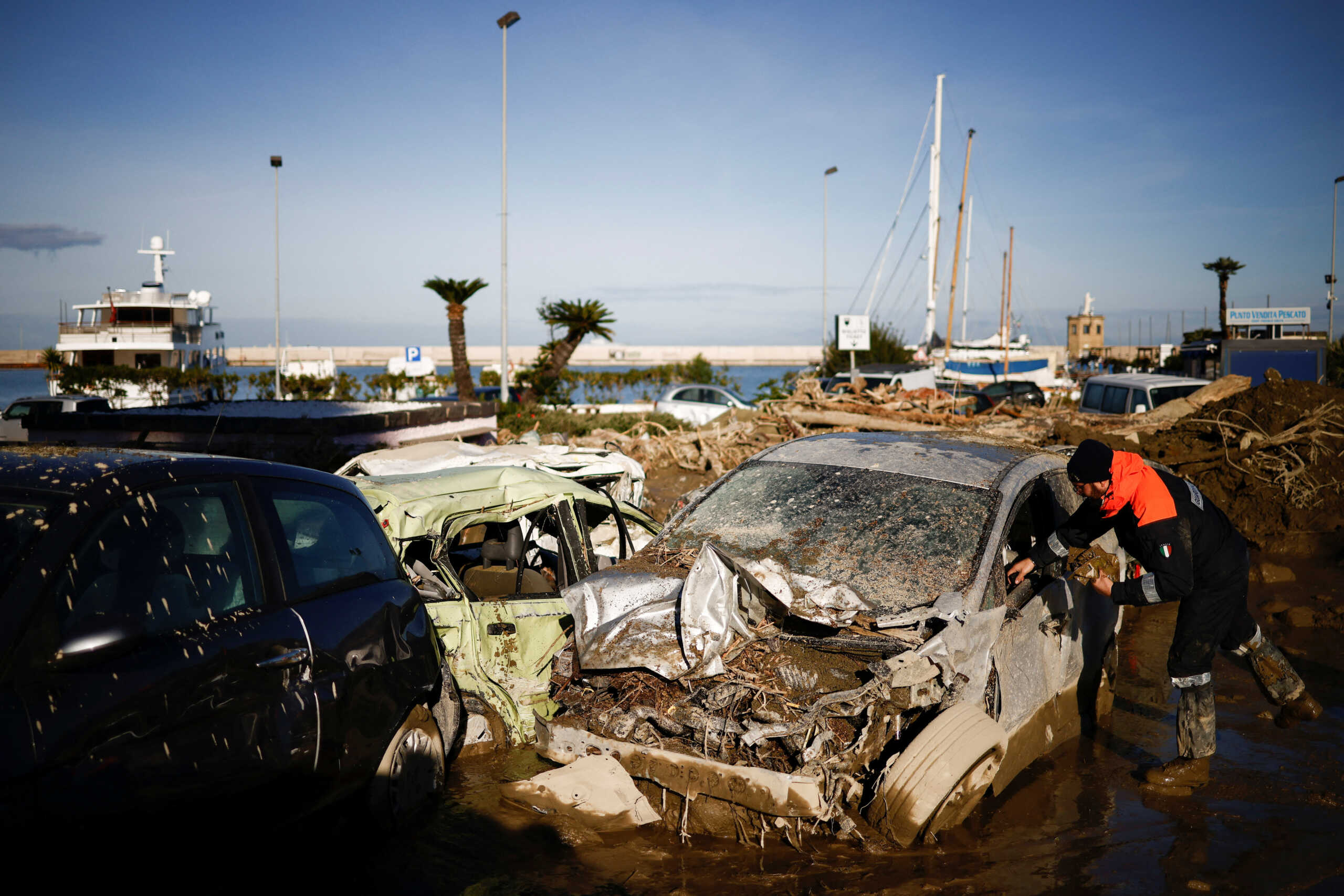 A member of the Coast Guard looks for documents inside a destroyed car, following a landslide on the Italian island of Ischia, Italy November 28, 2022. REUTERS
