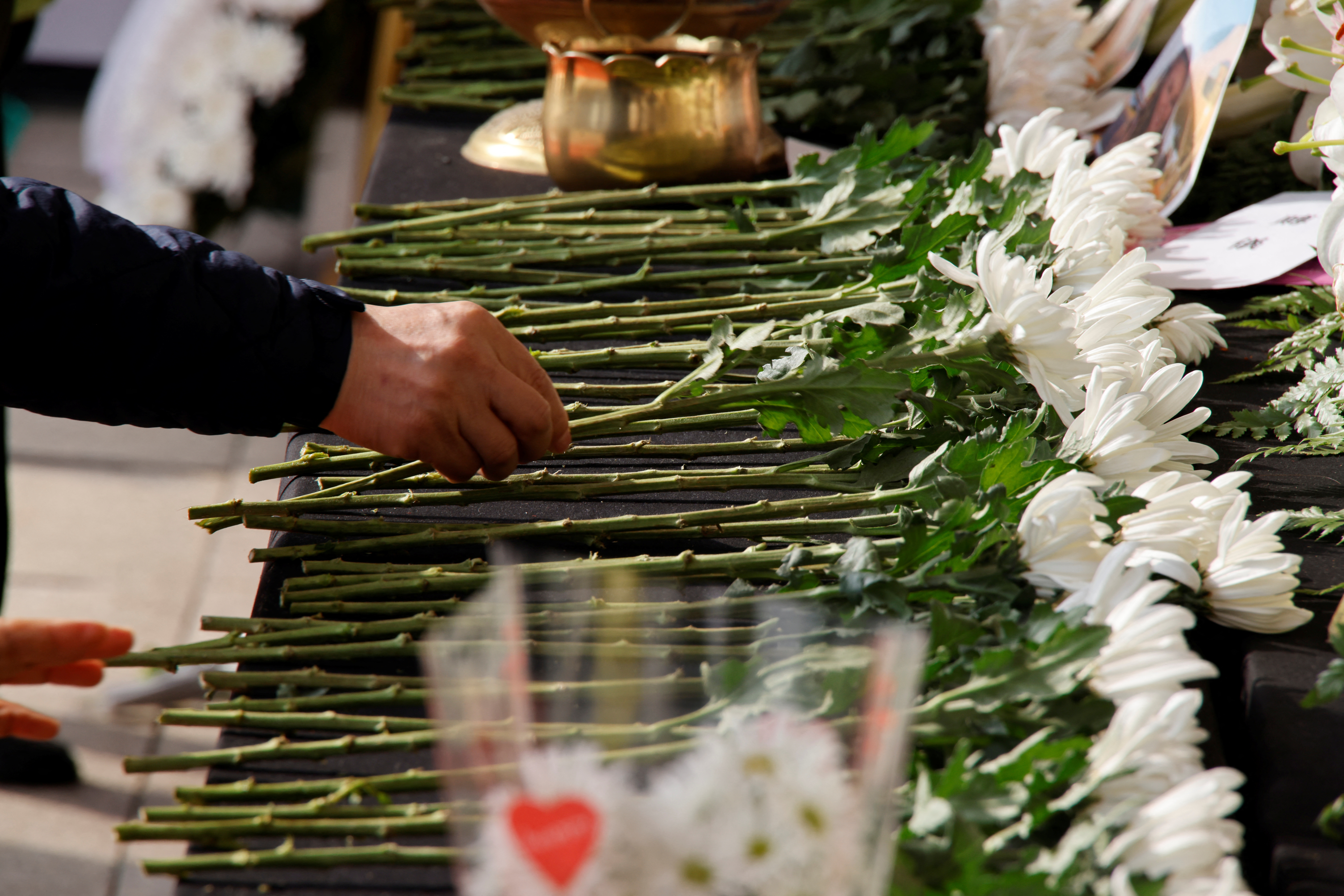 A person offers a flower at a group memorial for the victims of the crowd crush that happened during Halloween festivities, at Seoul City Hall Plaza in Seoul, South Korea, November 1, 2022. REUTERS