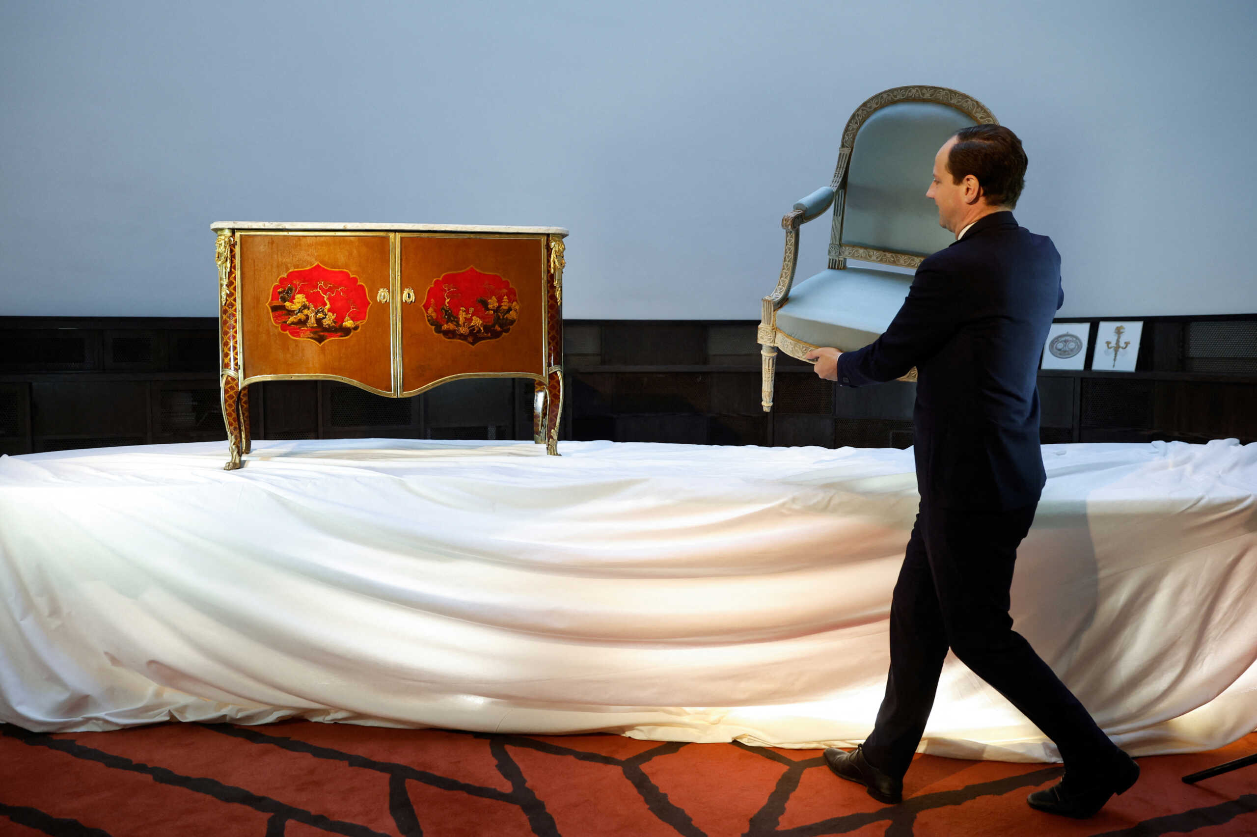 Simon de Monicault, Vice-President Christie's France, poses with a Royal Louis XVI Cream-Painted Armchair stamped by Georges Jacob, Cira 1788, and a Royal Late Louis XV Ormolu-Mounted Painted-Tole Commode stamped by Pierre Macret, Cira 1790, two pieces of furniture that belonged to the Queen of France, Marie-Antoinette, displayed before their auction at Christie's auction house in Paris, France, November 16, 2022.  REUTERS