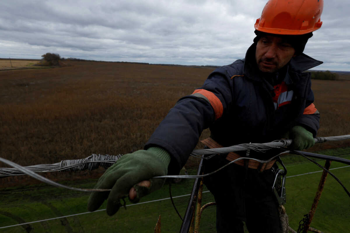 FILE PHOTO: An electrician works to repair an electricity power line that was damaged from shelling above a former battlefield, amid Russia's attack on Ukraine, in Kharkiv region, Ukraine, October 21, 2022. REUTERS