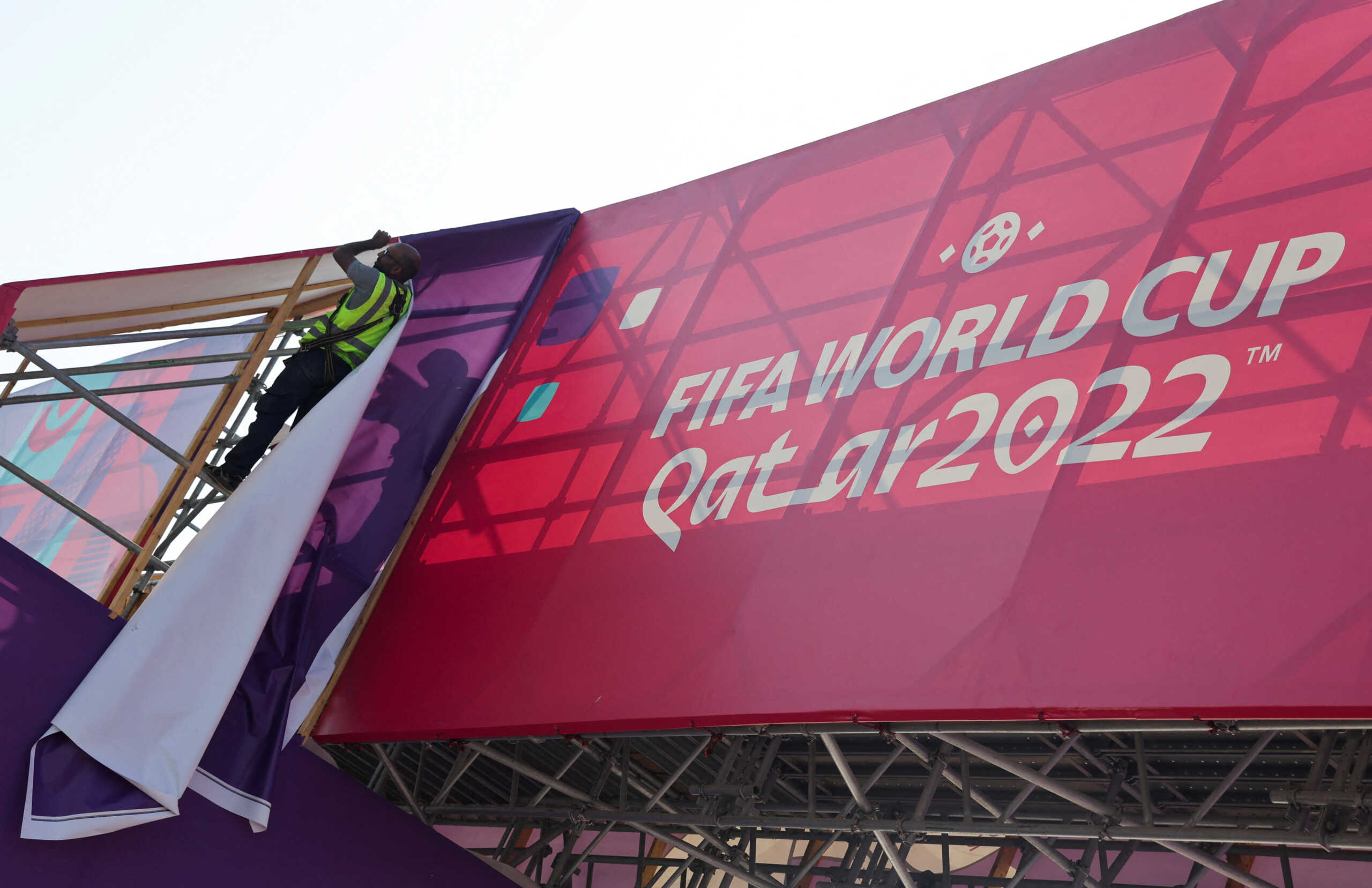 A worker fixes banners at Souq Waqif, which has been decorated ahead of the FIFA World Cup 2022 soccer tournament in Doha, Qatar November 11, 2022. REUTERS