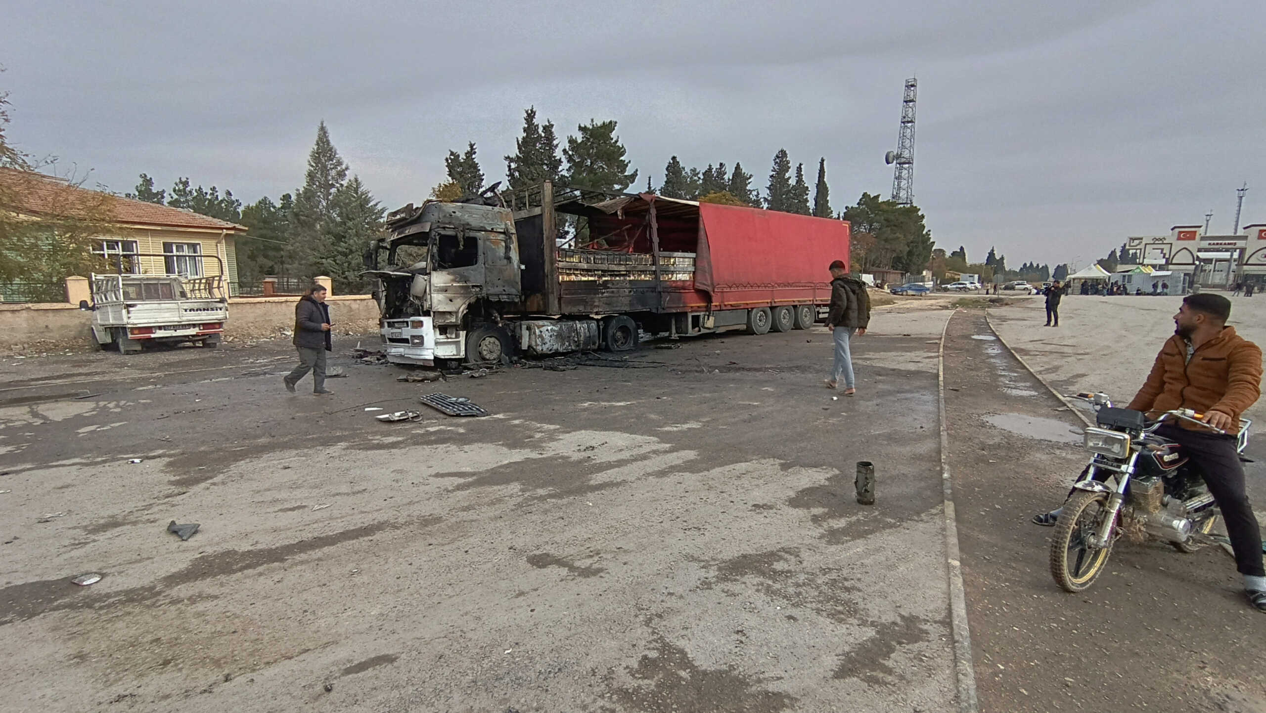 Locals inspect a burned truck hit by one of the rockets fired from northern Syria in the Karkamis district, near a border gate in Gaziantep province, Turkey November 21 2022 in this still image from video. IHA (Ihlas News Agency) via REUTERS ATTENTION EDITORS - THIS IMAGE HAS BEEN SUPPLIED BY A THIRD PARTY. NO RESALES. NO ARCHIVES.