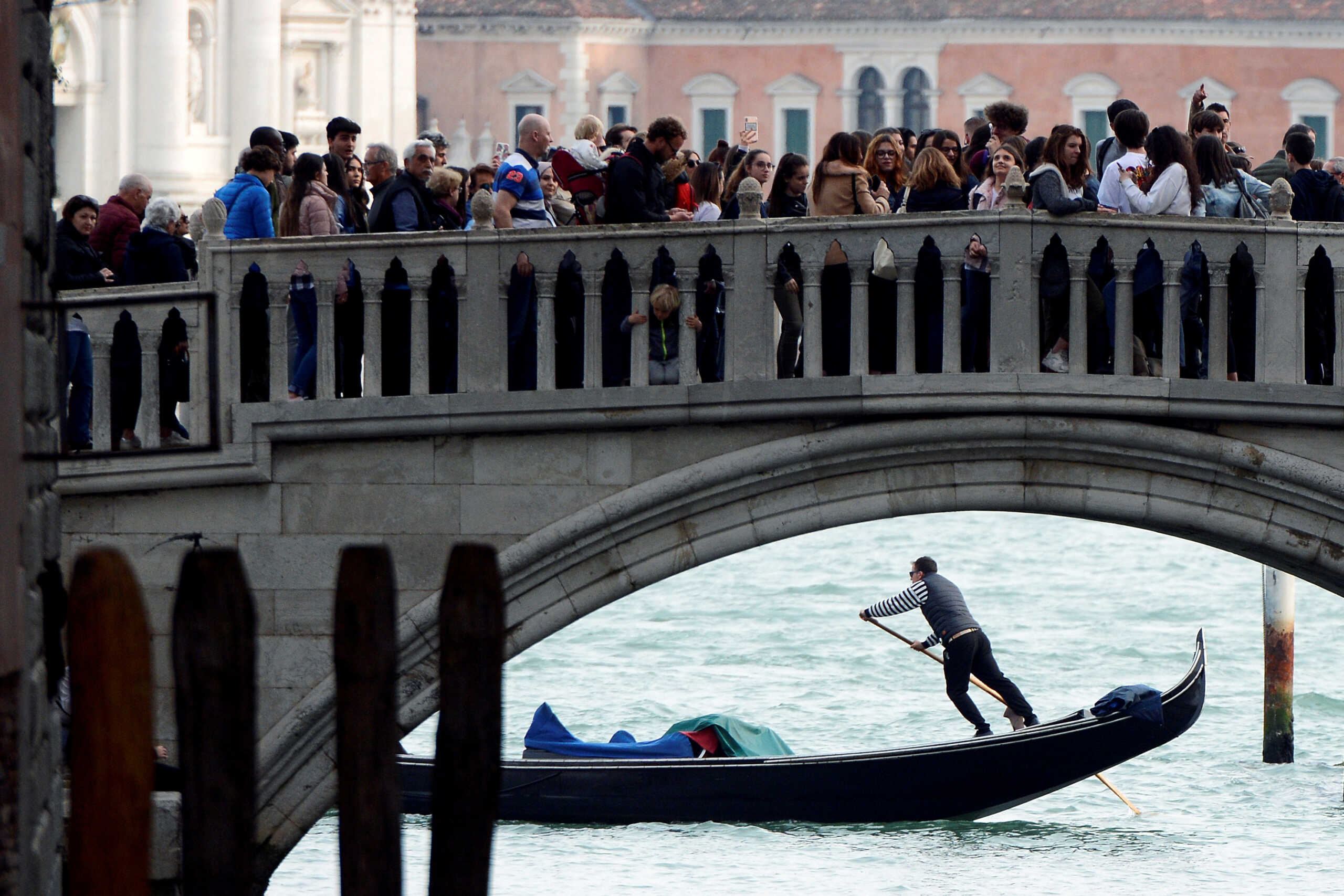 Tourists walk on a bridge as a gondolier rows his gondola near St.Marks Square in Venice, Italy, April 2, 2019. REUTERS