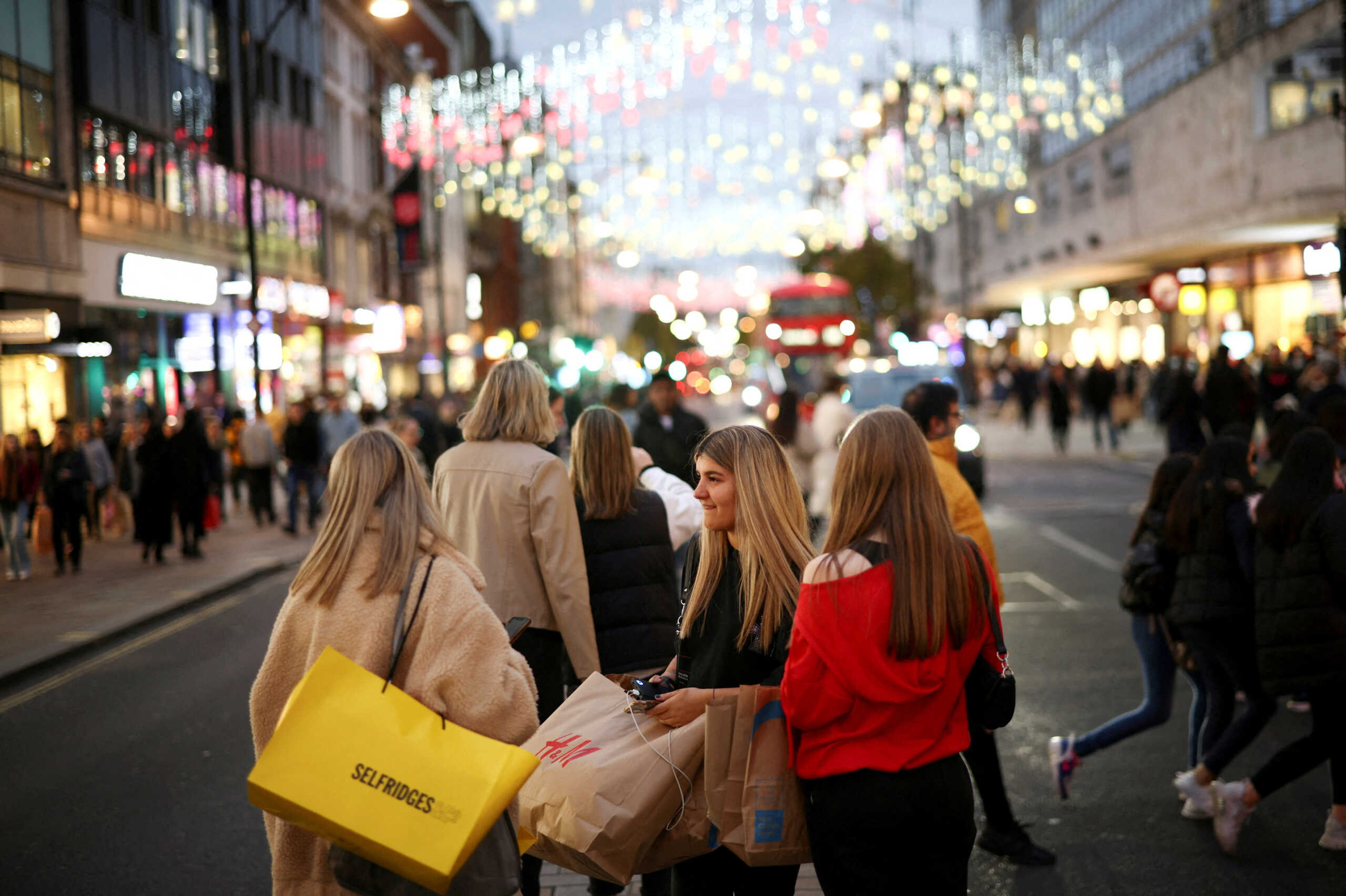 FILE PHOTO: People with shopping bags walk along Oxford Street illuminated with Christmas lights in London, Britain, November 13, 2021. REUTERS