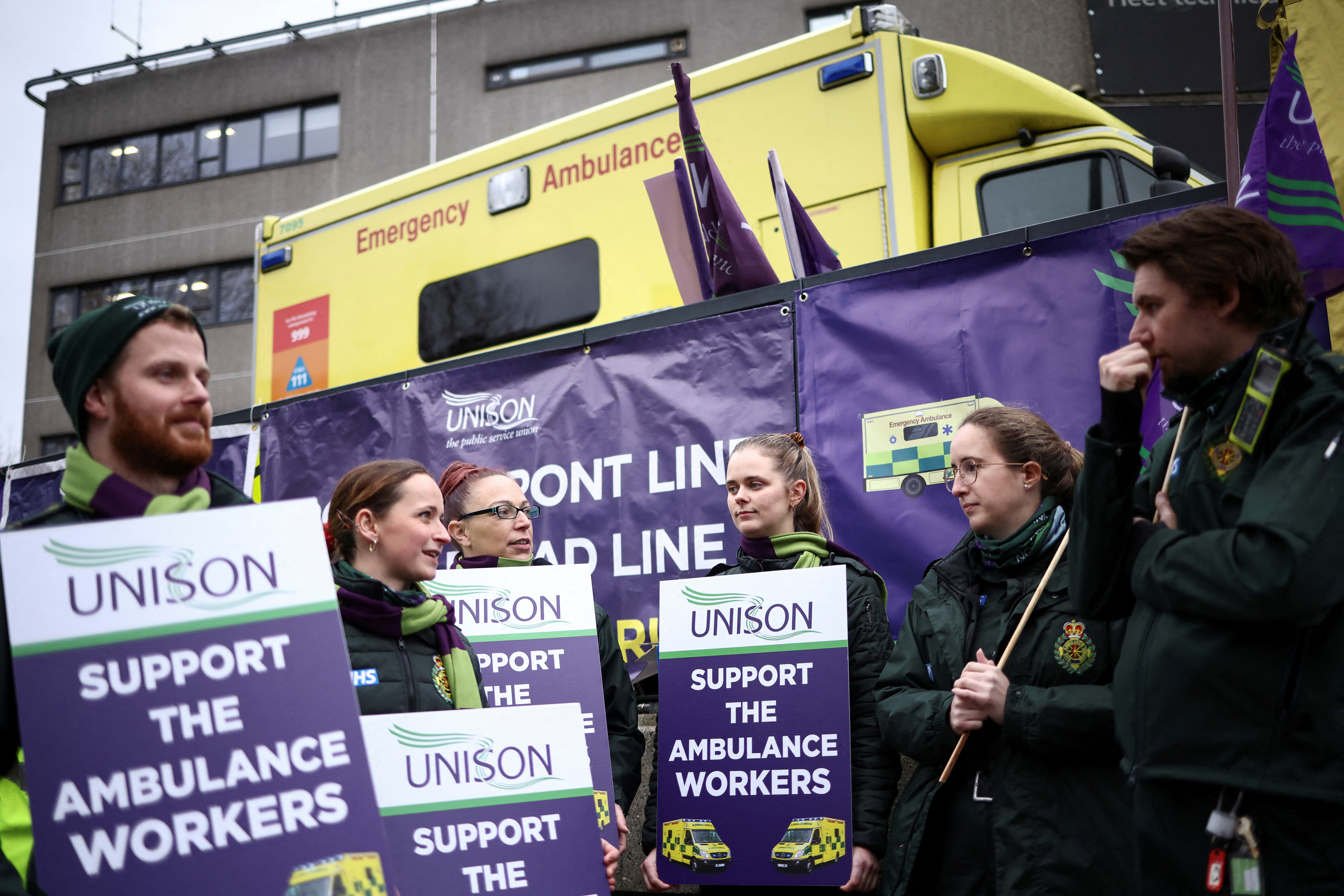 Ambulance workers hold signs as they take part in a strike, amid a dispute with the government over pay, outside NHS London Ambulance Service in London, Britain December 21, 2022. REUTERS