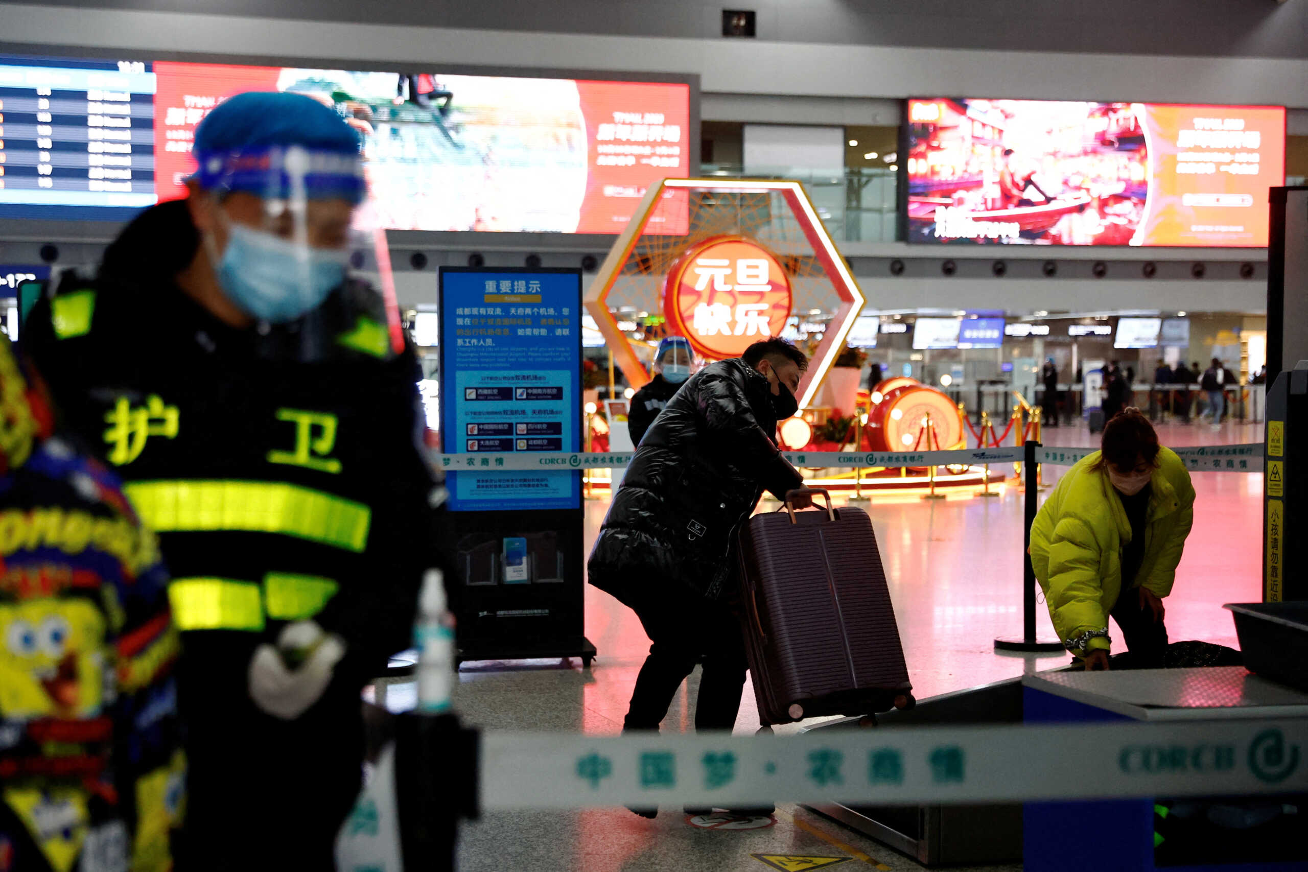 FILE PHOTO: A traveller holds his luggage at a checkpoint at Chengdu Shuangliu International Airport amid a wave of the coronavirus disease (COVID-19) infections, in Chengdu, Sichuan province, China December 30, 2022. REUTERS