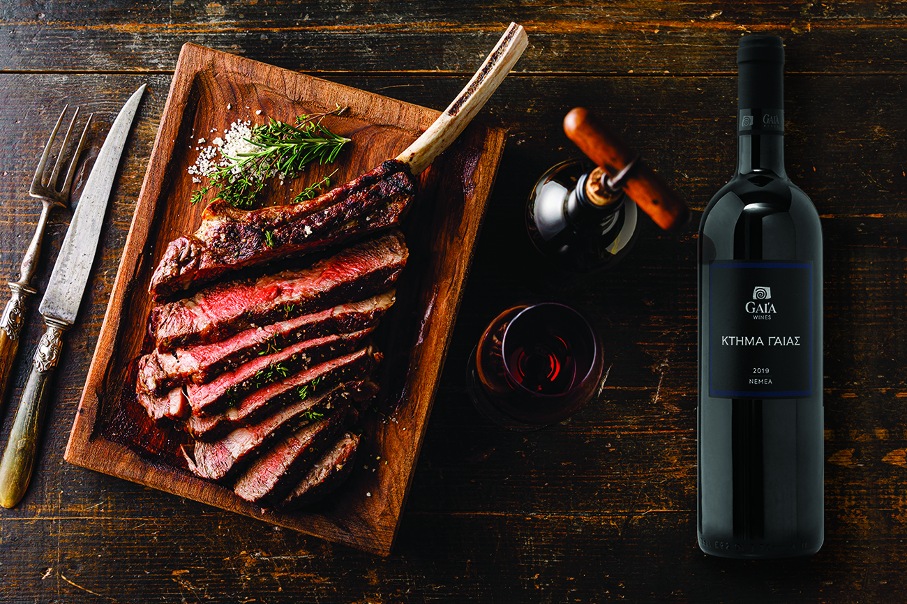 Grilled sliced Tomahawk Steak on bone and glass of Red wine on wooden background