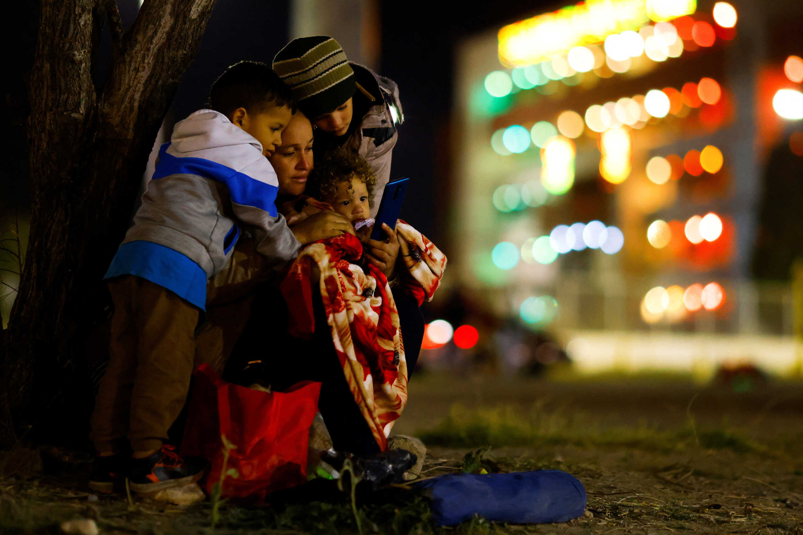 Sugeidy Medina, a Venezuelan migrant traveling with her children and husband and seeking asylum in the U.S., looks at a mobile phone near the Rio Bravo river, the border between Mexico and the U.S., as seen from Ciudad Juarez, Mexico December 21, 2022. REUTERS