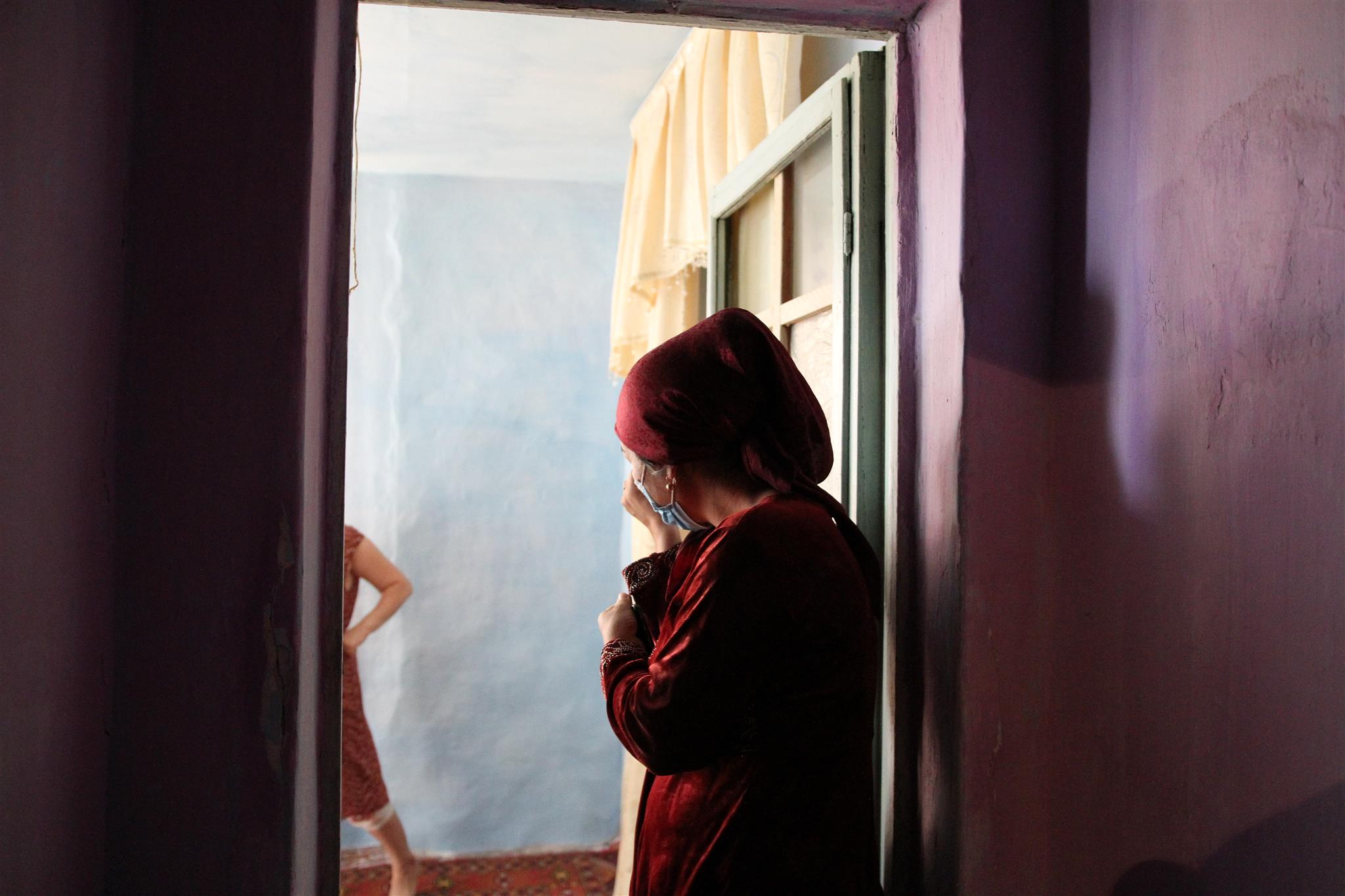 An Uzbek woman wearing a traditional red dress and head cover is pictured standing in her home in the Sirdaryo region in Uzbekistan on Sept. 20, 2020. Thomson Reuters Foundation