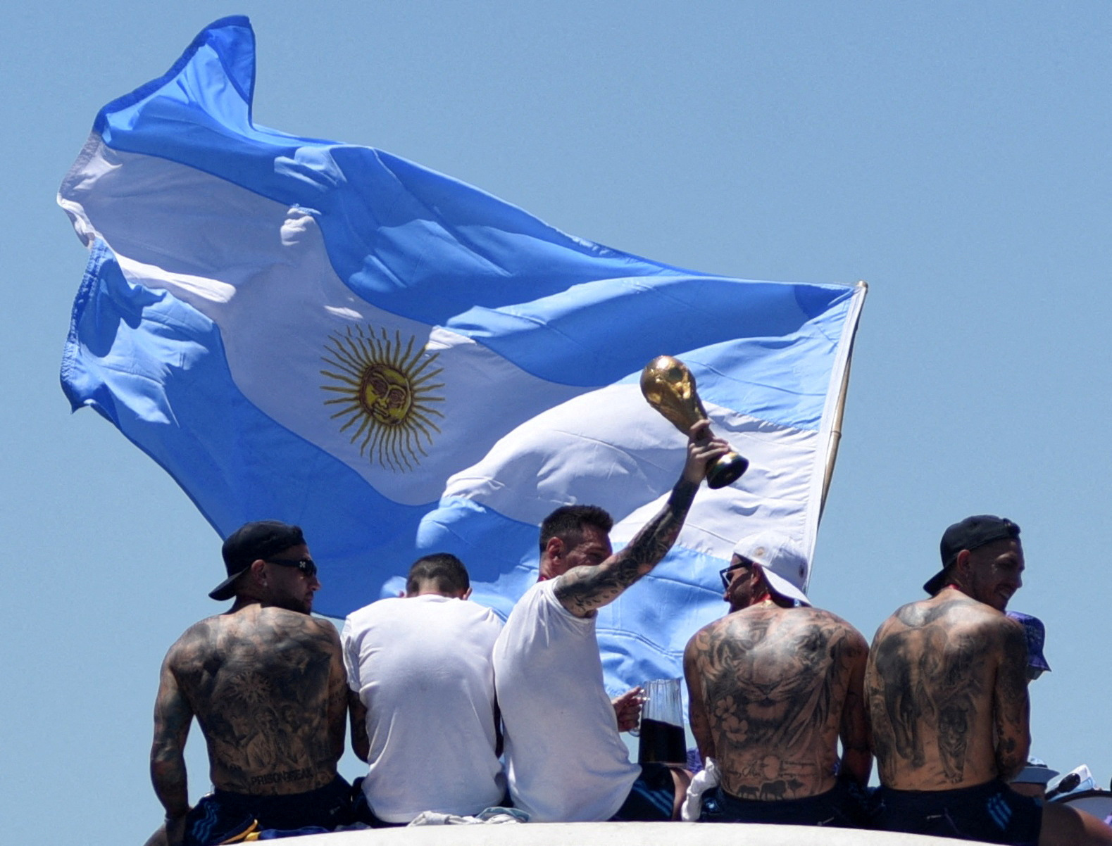 Soccer Football - FIFA World Cup Qatar 2022 - Argentina Victory Parade after winning the World Cup - Buenos Aires, Argentina - December 20, 2022  Argentina's Lionel Messi and teammates celebrate on the bus with the World Cup trophy and the flag of Argentina during the victory parade REUTERS