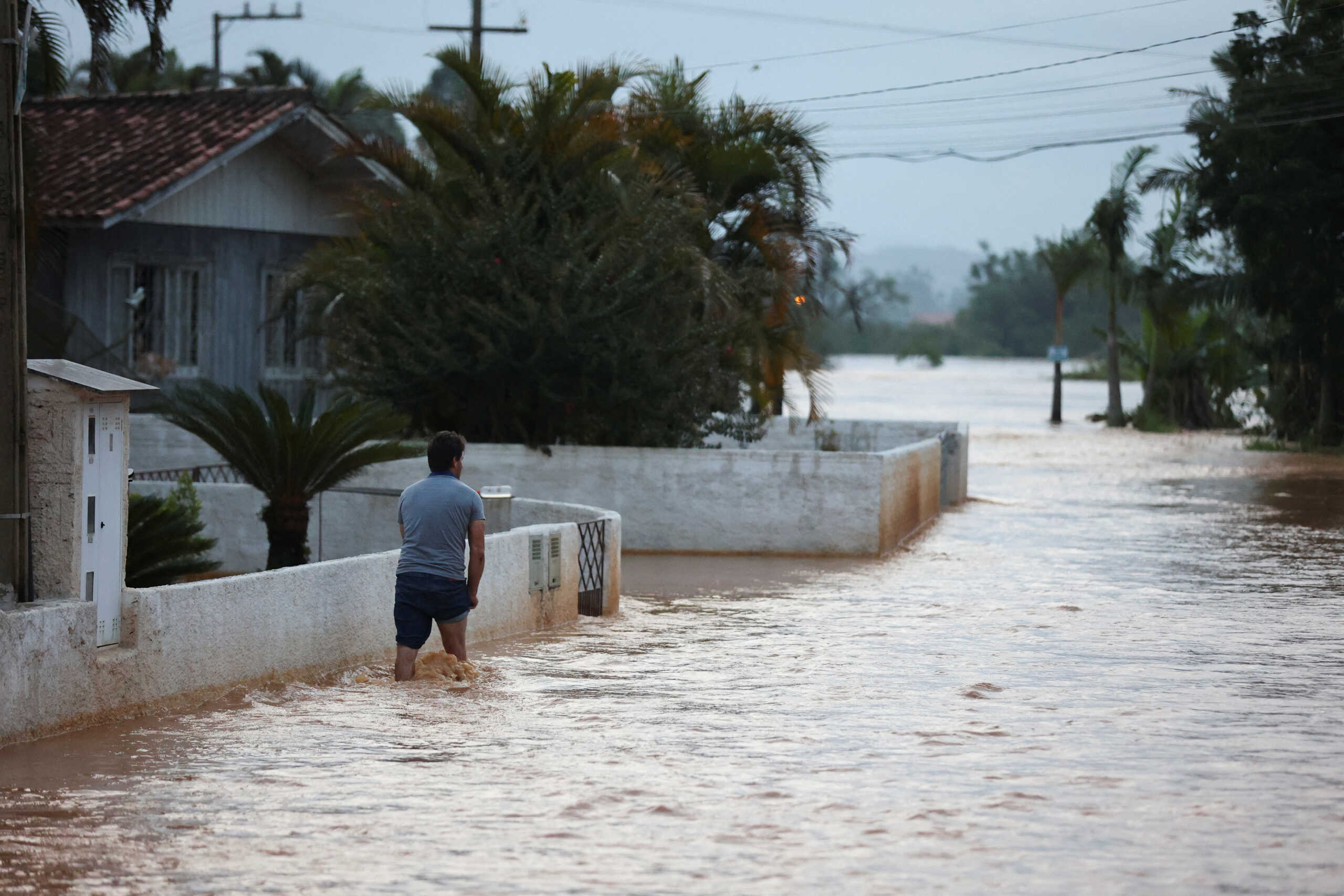 A man walks through a flooded street after heavy rains in Canelinha, in Santa Catarina state, Brazil, December 1, 2022. REUTERS