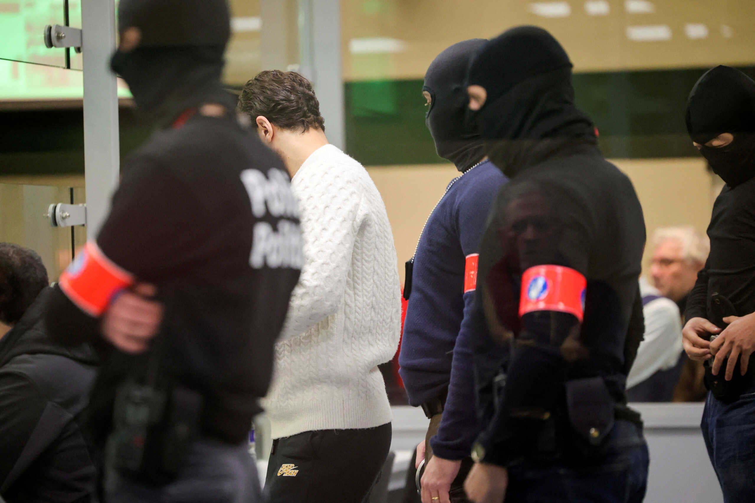 Special police stand behind defendants in a specially designed glass box during the start of the trial for the Brussels attacks, that took place on March 22, 2016, at the Justitia building in Brussels, Monday, Dec. 5, 2022. Olivier Matthys