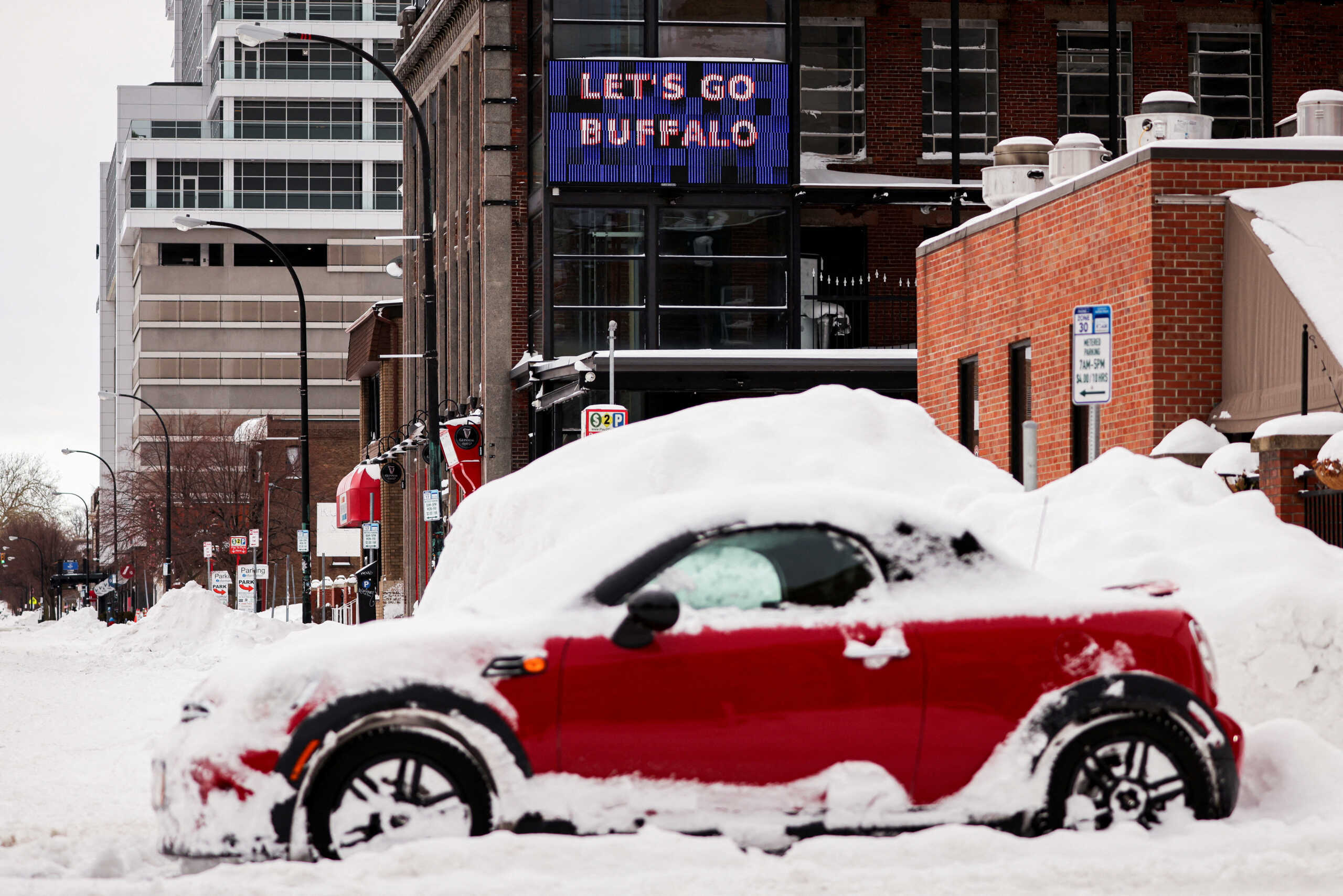 A "let’s go Buffalo" sign is seen behind an abandoned car on the road following a winter storm in Buffalo, New York, U.S., December 27, 2022.  REUTERS