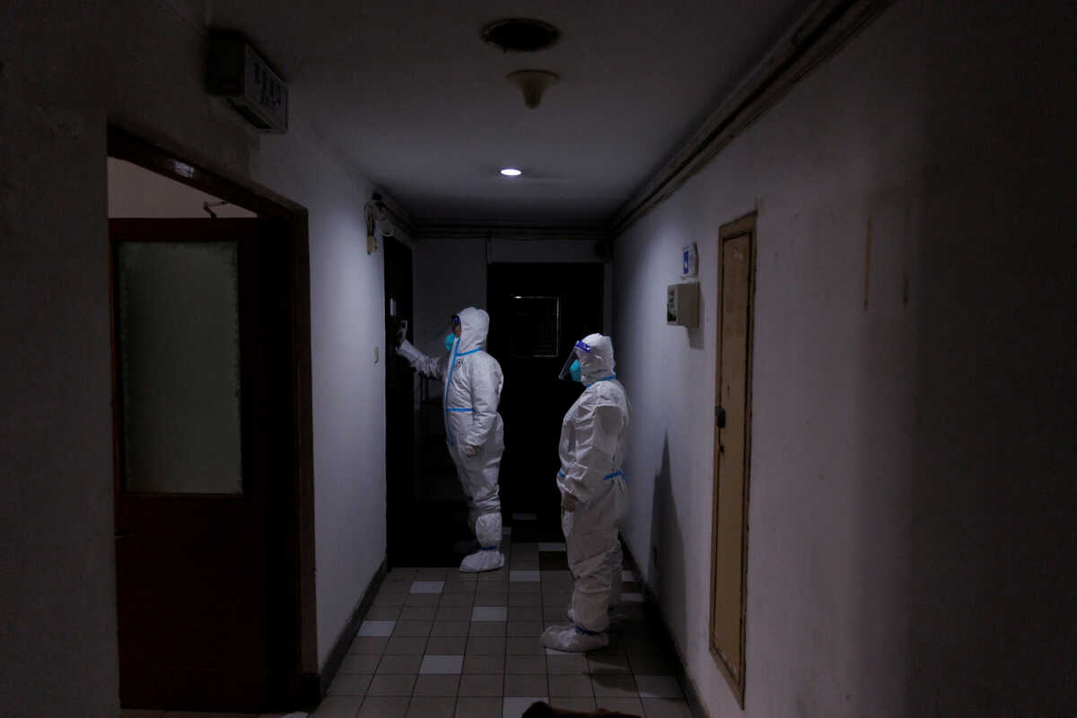 FILE PHOTO: Pandemic prevention workers in protective suits knock on a resident's door in an apartment building that went into lockdown as coronavirus disease (COVID-19) outbreaks continue in Beijing, December 2, 2022. REUTERS