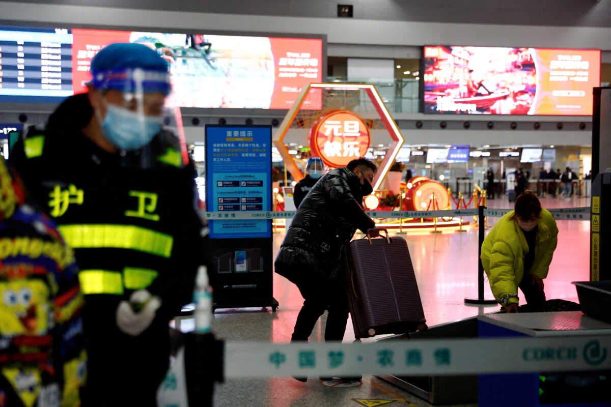 FILE PHOTO: A traveller holds his luggage at a checkpoint at Chengdu Shuangliu International Airport amid a wave of the coronavirus disease (COVID-19) infections, in Chengdu, Sichuan province, China December 30, 2022. REUTERS