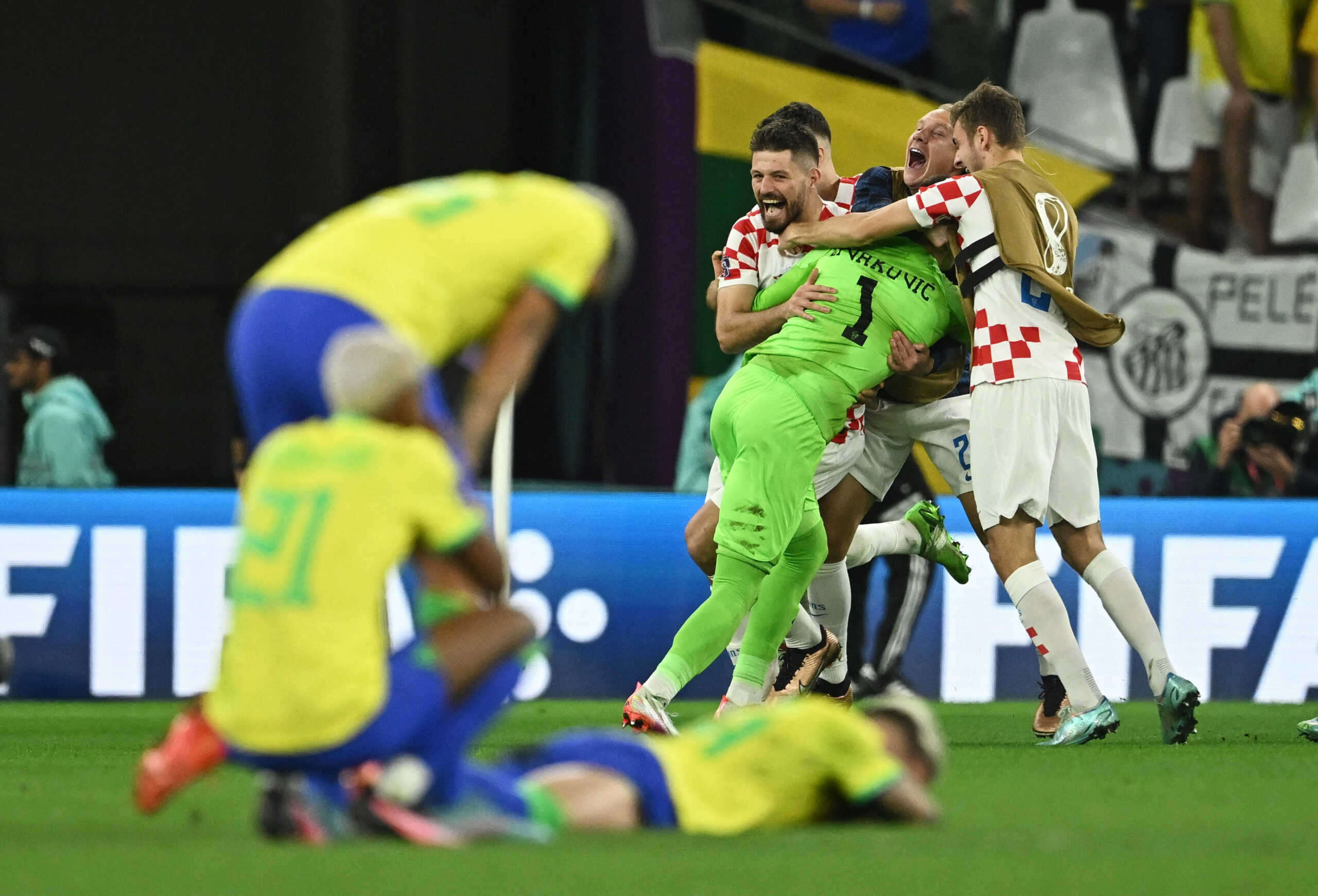 Soccer Football - FIFA World Cup Qatar 2022 - Quarter Final - Croatia v Brazil - Education City Stadium, Doha, Qatar - December 9, 2022 Croatia's Dominik Livakovic celebrates with teammates after winning the penalty shootout progressing to the semi finals as Brazil players look dejected REUTERS
