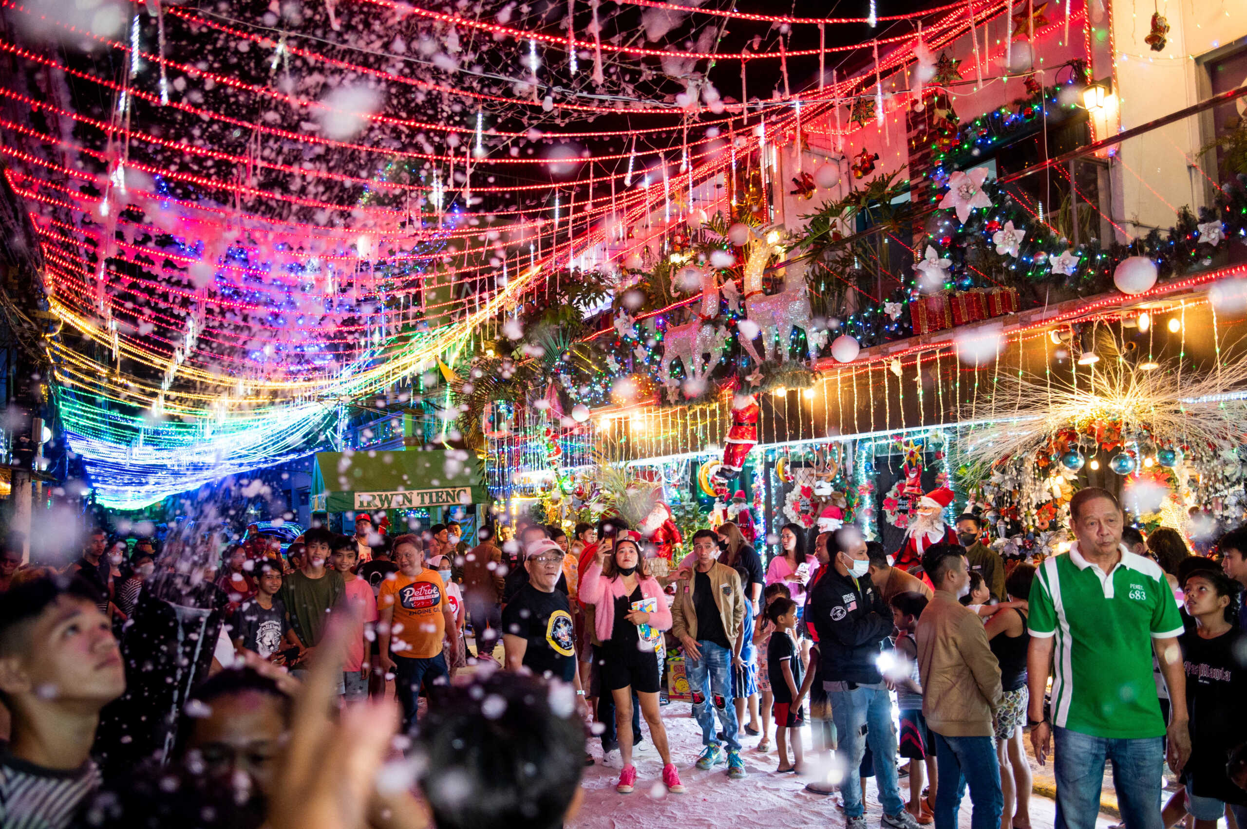 People enjoy fake snow outside a Christmas-themed house, in Manila, Philippines, December 11, 2022. REUTERS