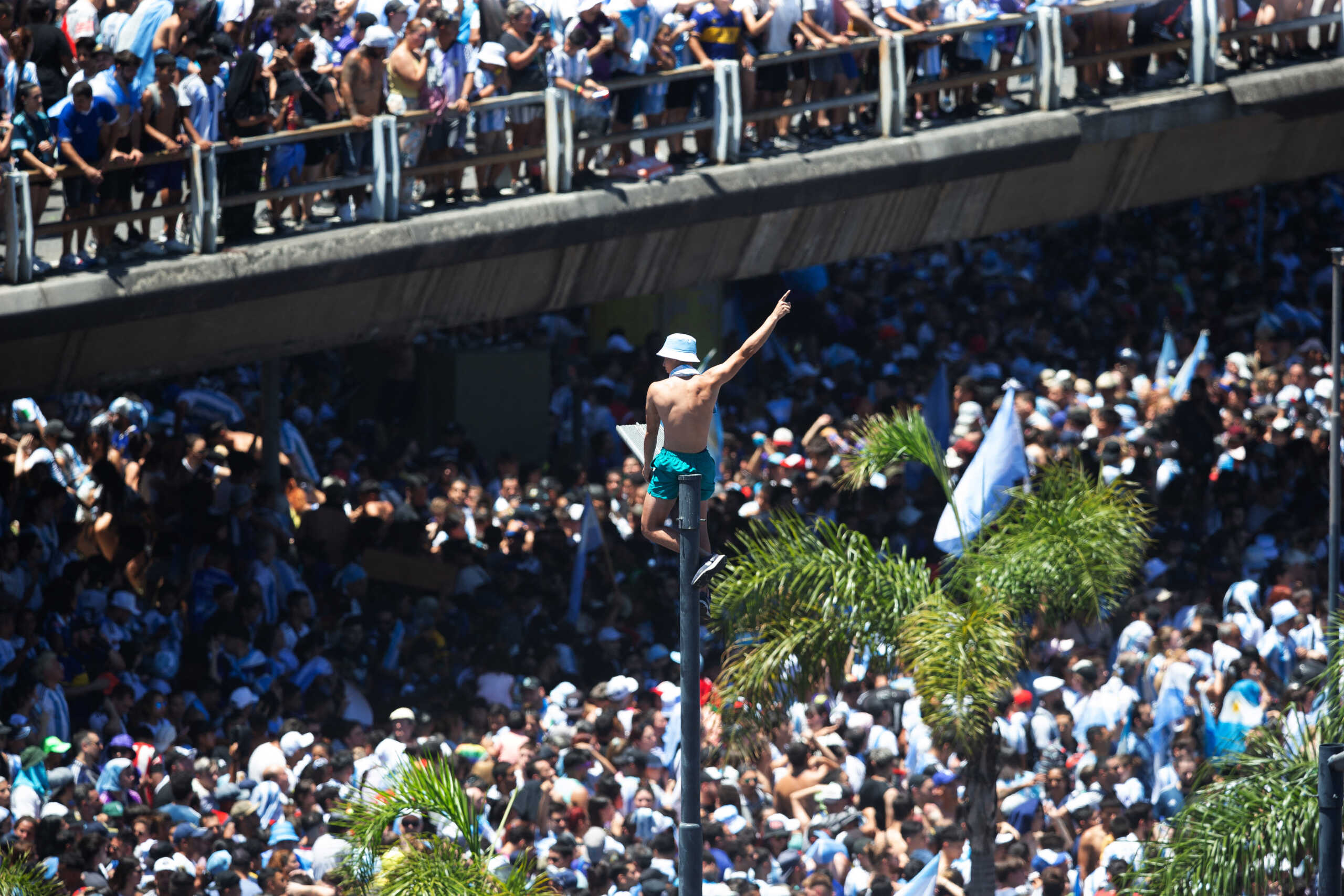 Soccer Football - FIFA World Cup Qatar 2022 - Argentina Victory Parade after winning the World Cup - Buenos Aires, Argentina - December 20, 2022  An Argentina fan is pictured on top of a street lamp as fans celebrate below during the victory parade REUTERS