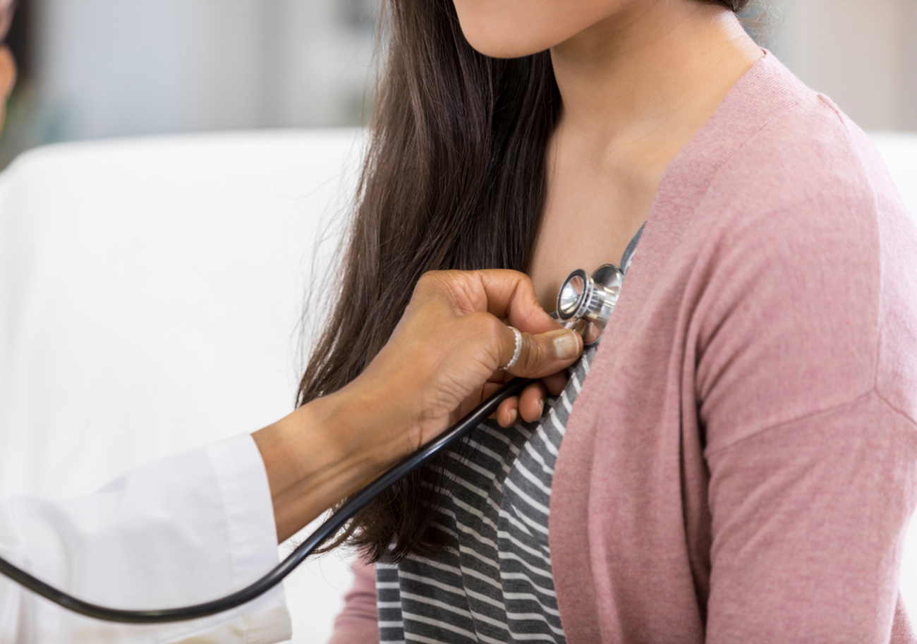 Unrecognizable doctor listens to a teenage patient's heartbeat