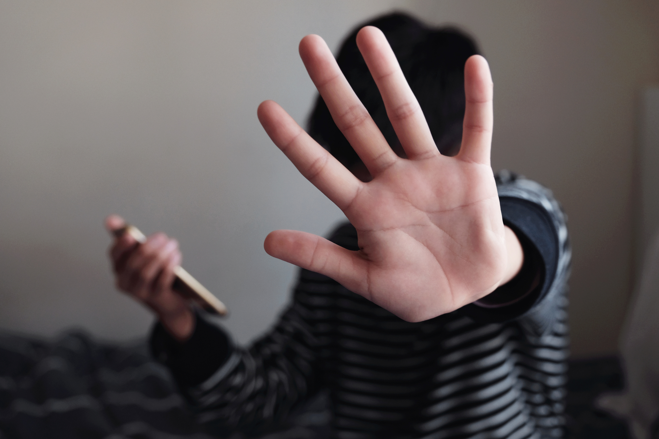 Young Asian preteen teenager boy holding a smartphone and showing a stop sign with his hand, Stop cyber bullying concept, mental health problem
