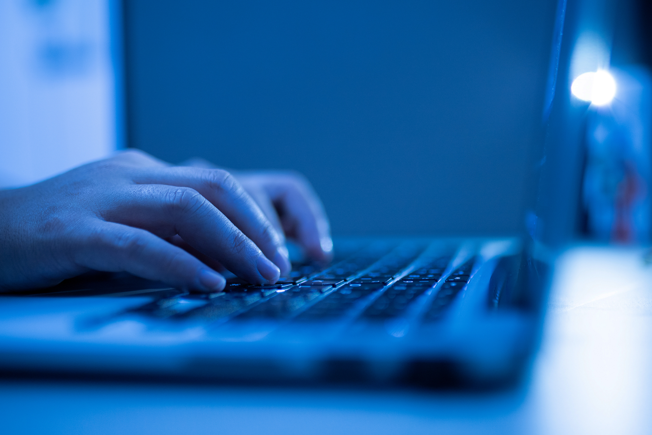 Hand of a man using laptop computer for hacking or steal data at night in office. Hacking concept