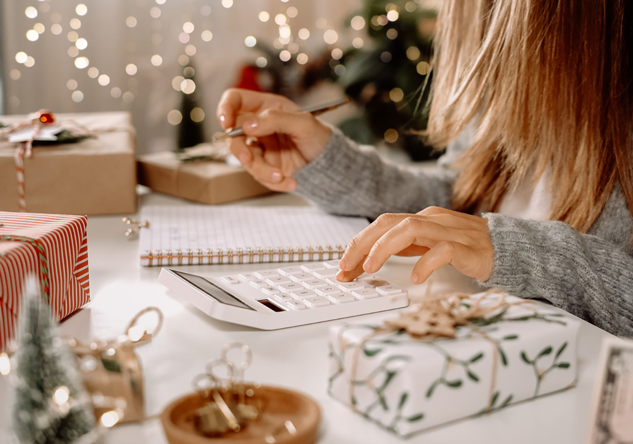 Girl counting US Dollar bills, using calculator, and writing expenses. Woman doing budget, estimating money balance for shopping spree. Female accountant paying taxes. Girl counting Christmas gifts.