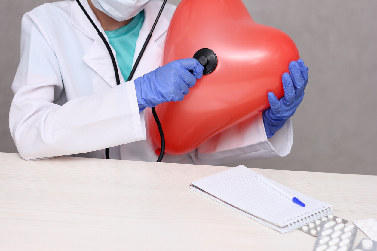 Cardiology and heart disease idea.ctor listening to a large inflatable heart with a stethoscope. Cardiology and heart disease idea.