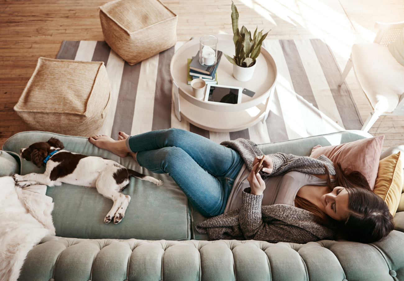 Shot of an attractive young woman using her cellphone while relaxing at home