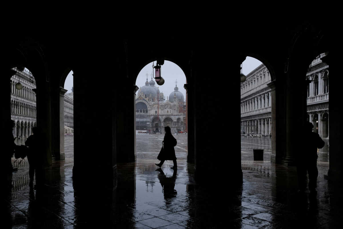FILE PHOTO: People walk in St. Mark's Square during exceptional high tide as the flood barriers known as Mose are raised, in Venice, Italy, November 22, 2022. REUTERS