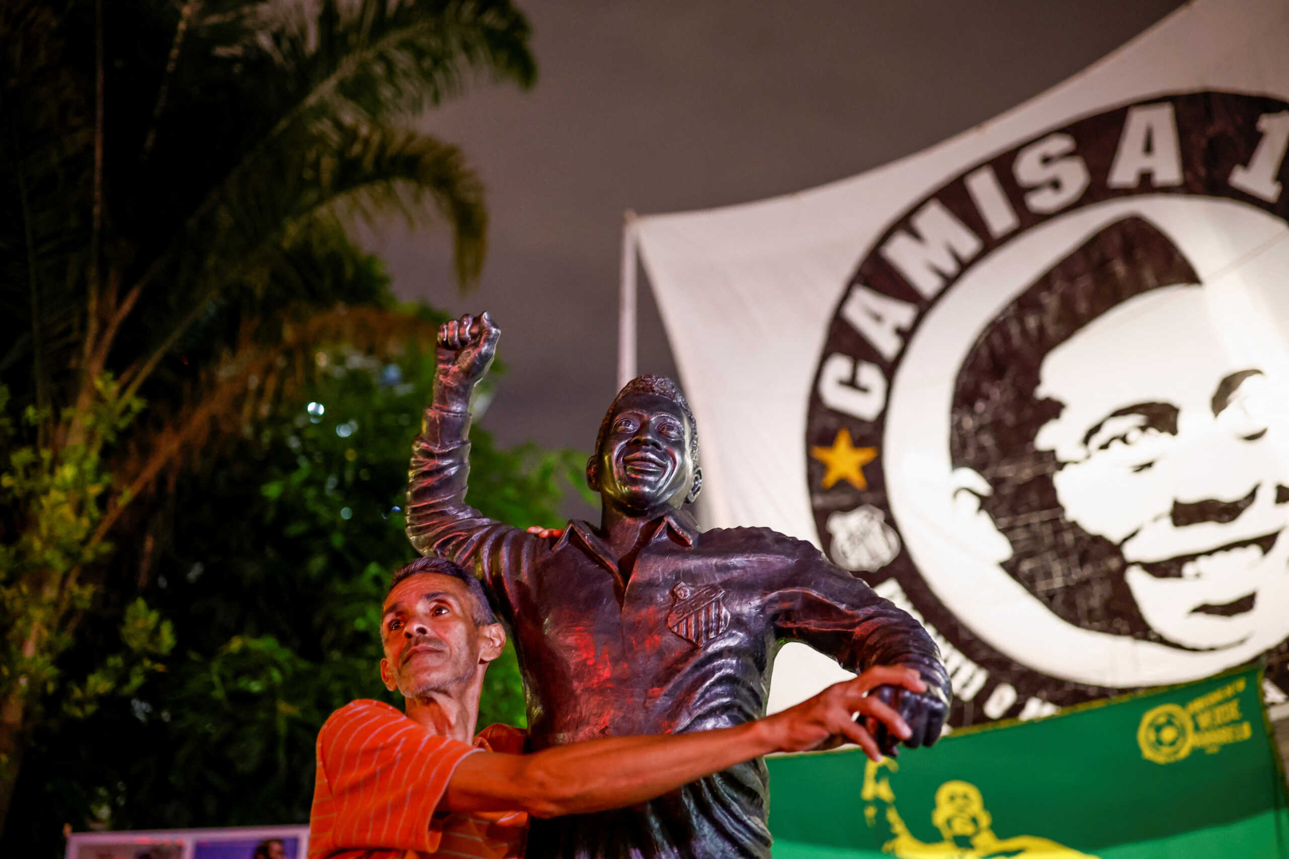 A man touches a statue depicting Brazilian soccer legend Pele in Santos, Brazil, December 29, 2022. REUTERS