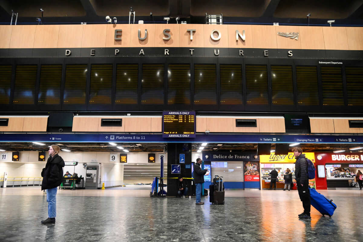 Passengers stand below a blank departure display board while they wait at the concourse of Euston station, as rail workers strike over pay and terms, in London, Britain December 13, 2022. REUTERS