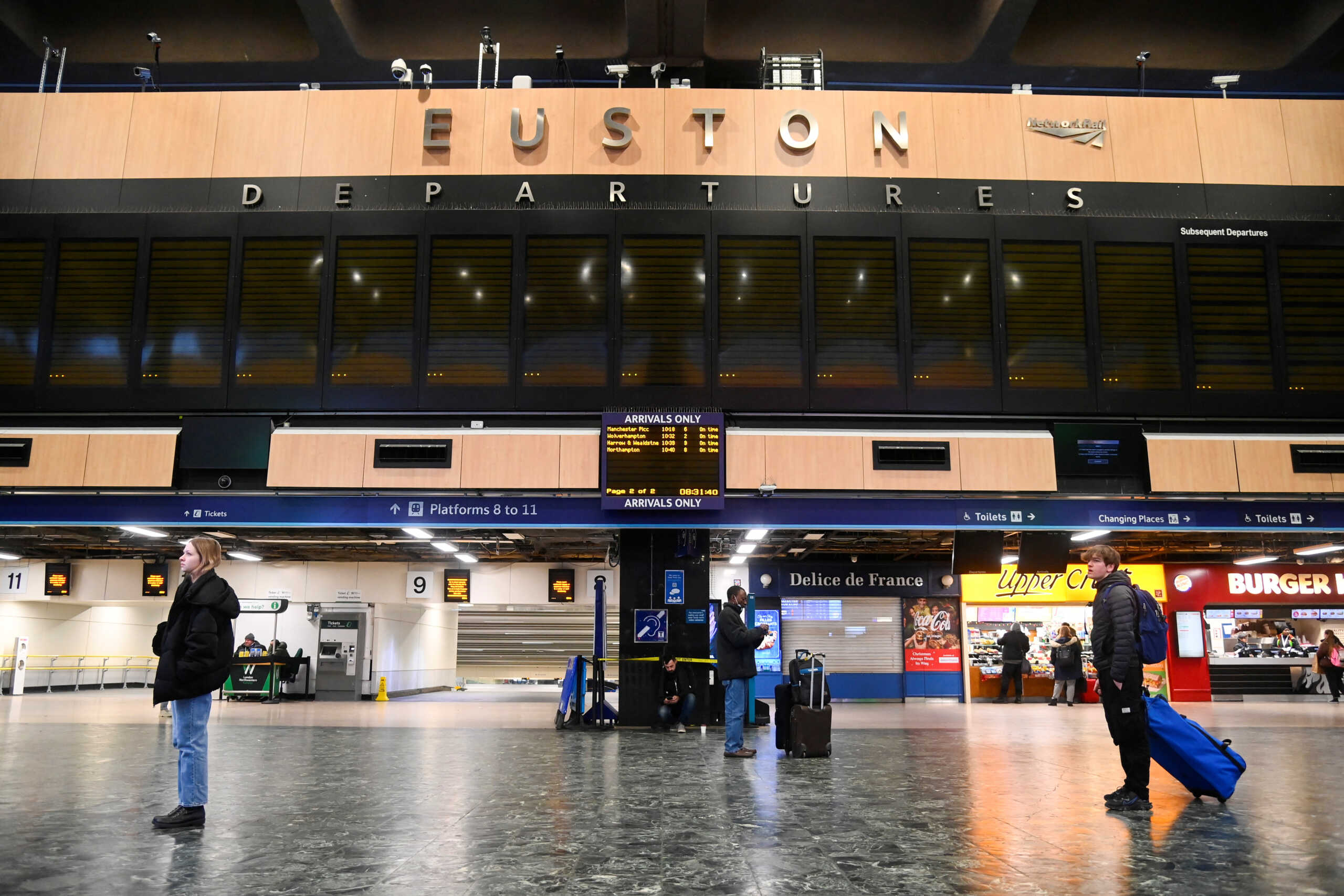 Passengers stand below a blank departure display board while they wait at the concourse of Euston station, as rail workers strike over pay and terms, in London, Britain December 13, 2022. REUTERS