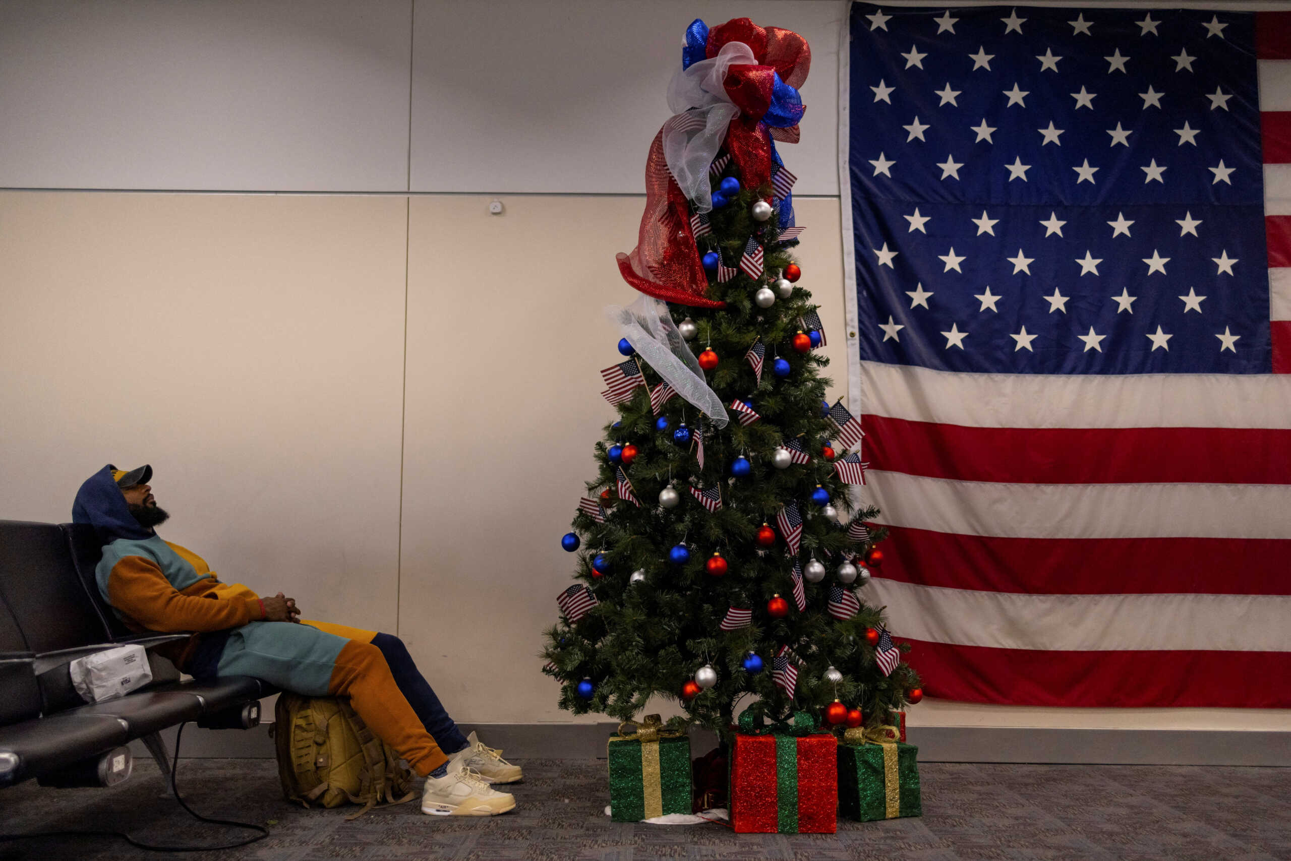 A man sleeps next to a Christmas tree at the Atlanta international airport in Atlanta, Georgia, U.S., December 7, 2022. REUTERS