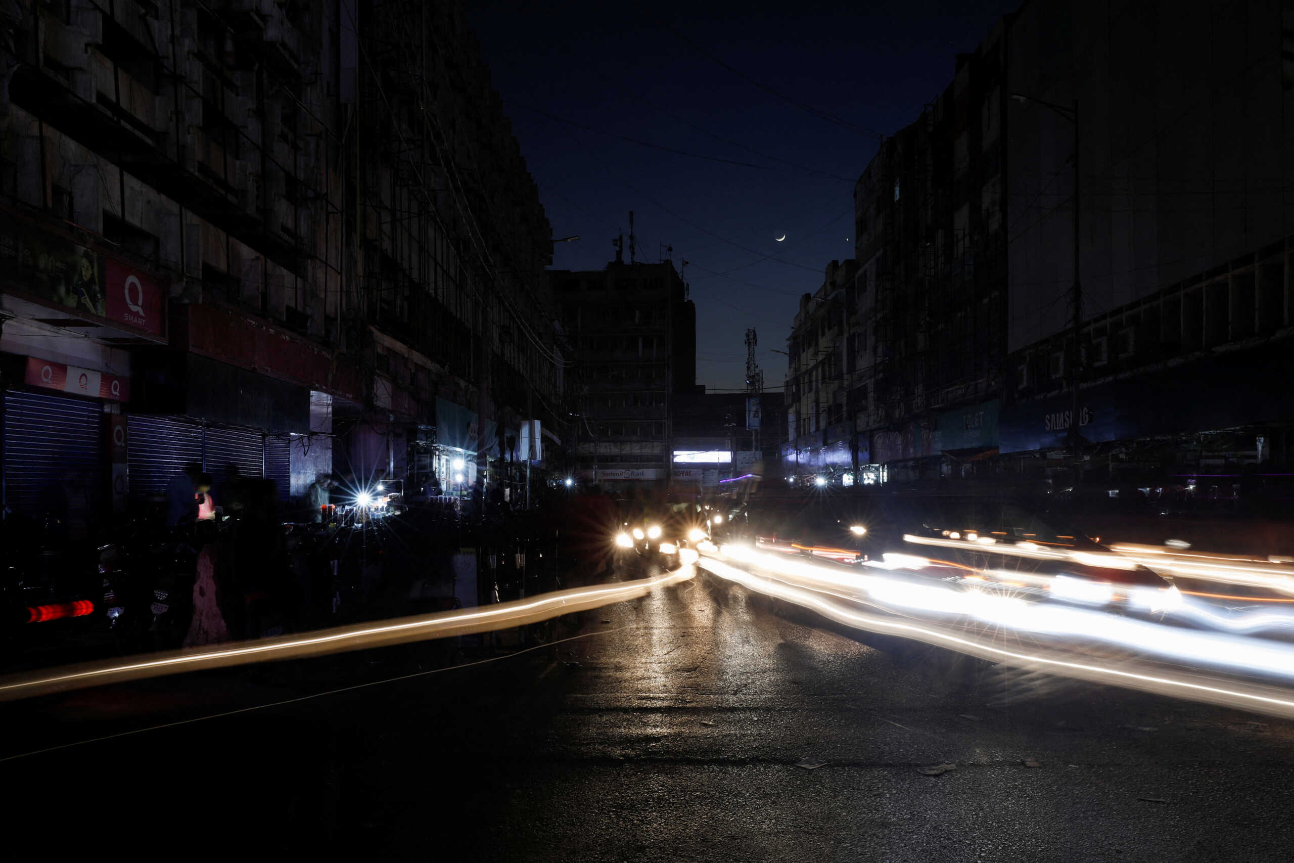 Vehicle lights cause light streaks on the road along a market, during country-wide power breakdown in Karachi, Pakistan January 23, 2023. REUTERS