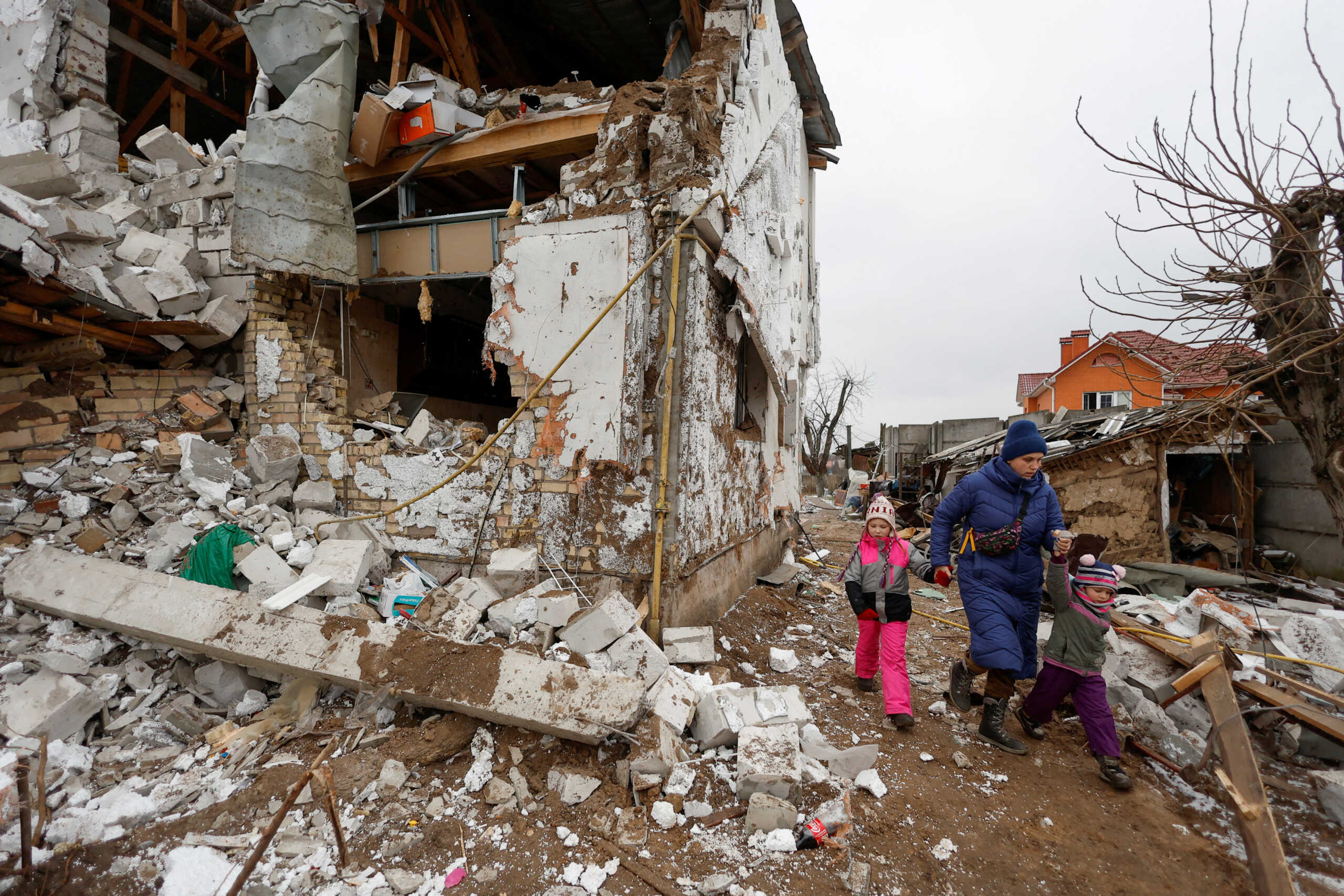 Local woman with kids walks next to a residential house damaged by a Russian military strike, amid Russia's attack on Ukraine, in the town of Hlevakha, outside Kyiv, Ukraine January 26, 2023.  REUTERS