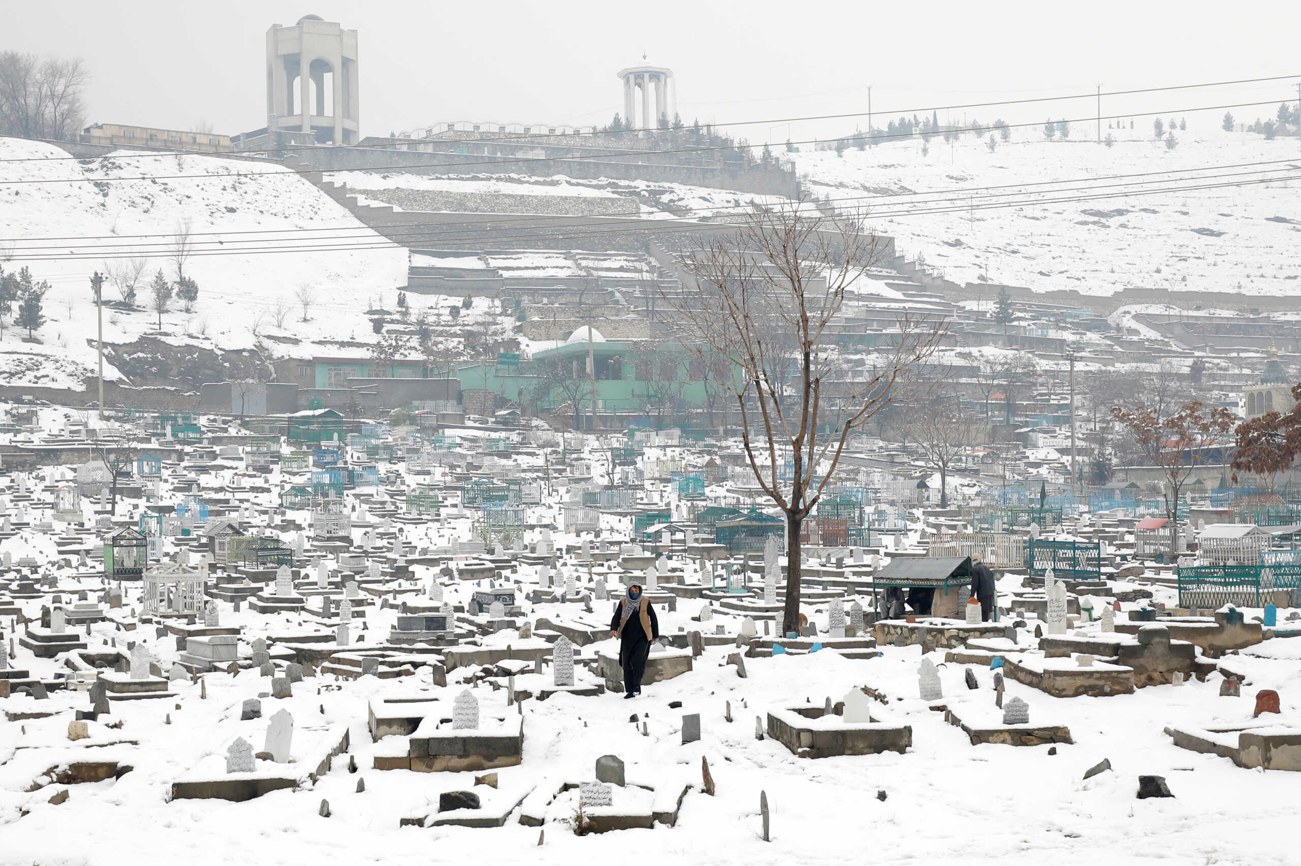 An Afghan man walks on a snow-covered cemetery in Kabul, Afghanistan, January 11, 2023. REUTERS
