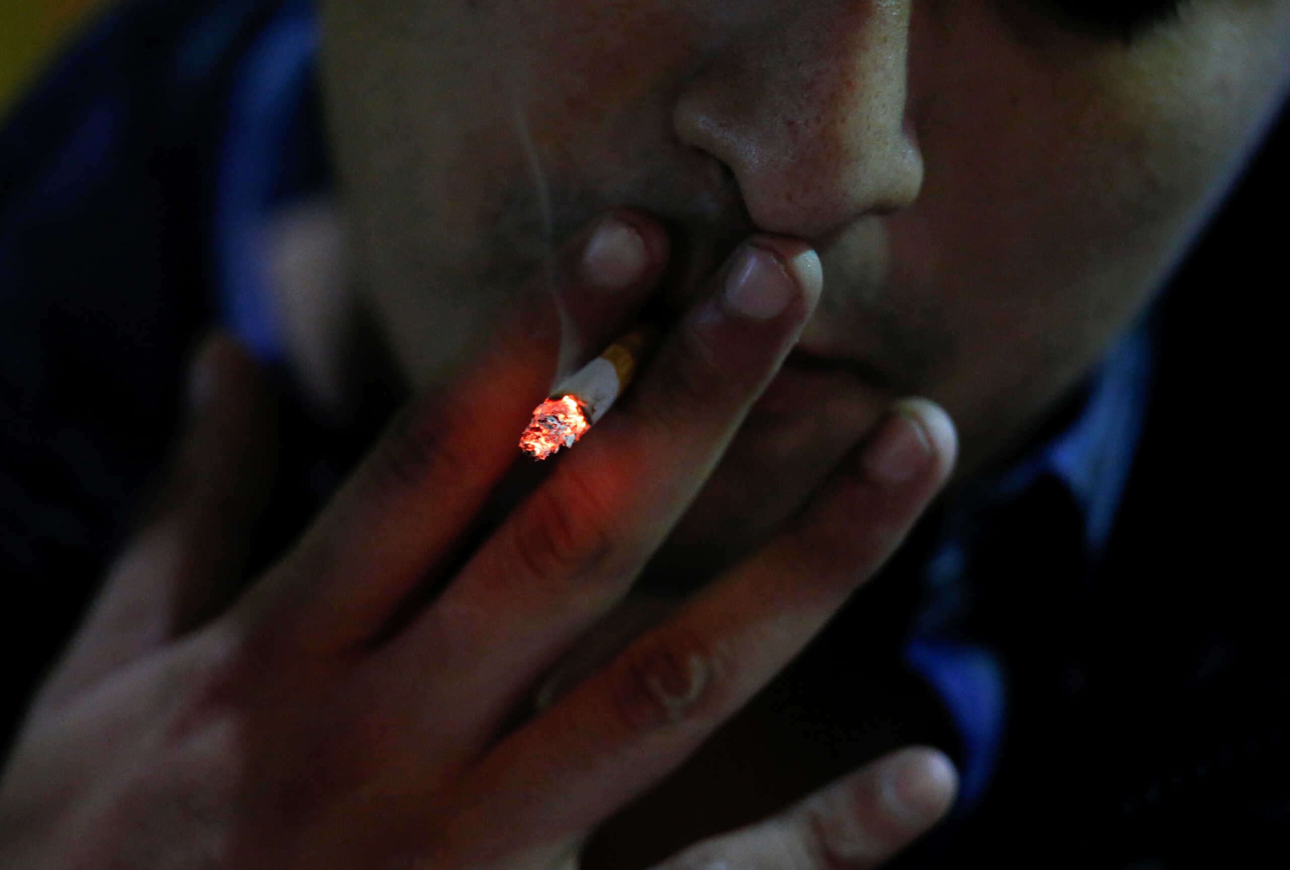 A man smokes a cigarette outside a bar, before smoking was banned in public spaces according to a reform of the Mexican government's regulation of the general law for tobacco control, in Monterrey, Mexico January 14, 2023. REUTERS