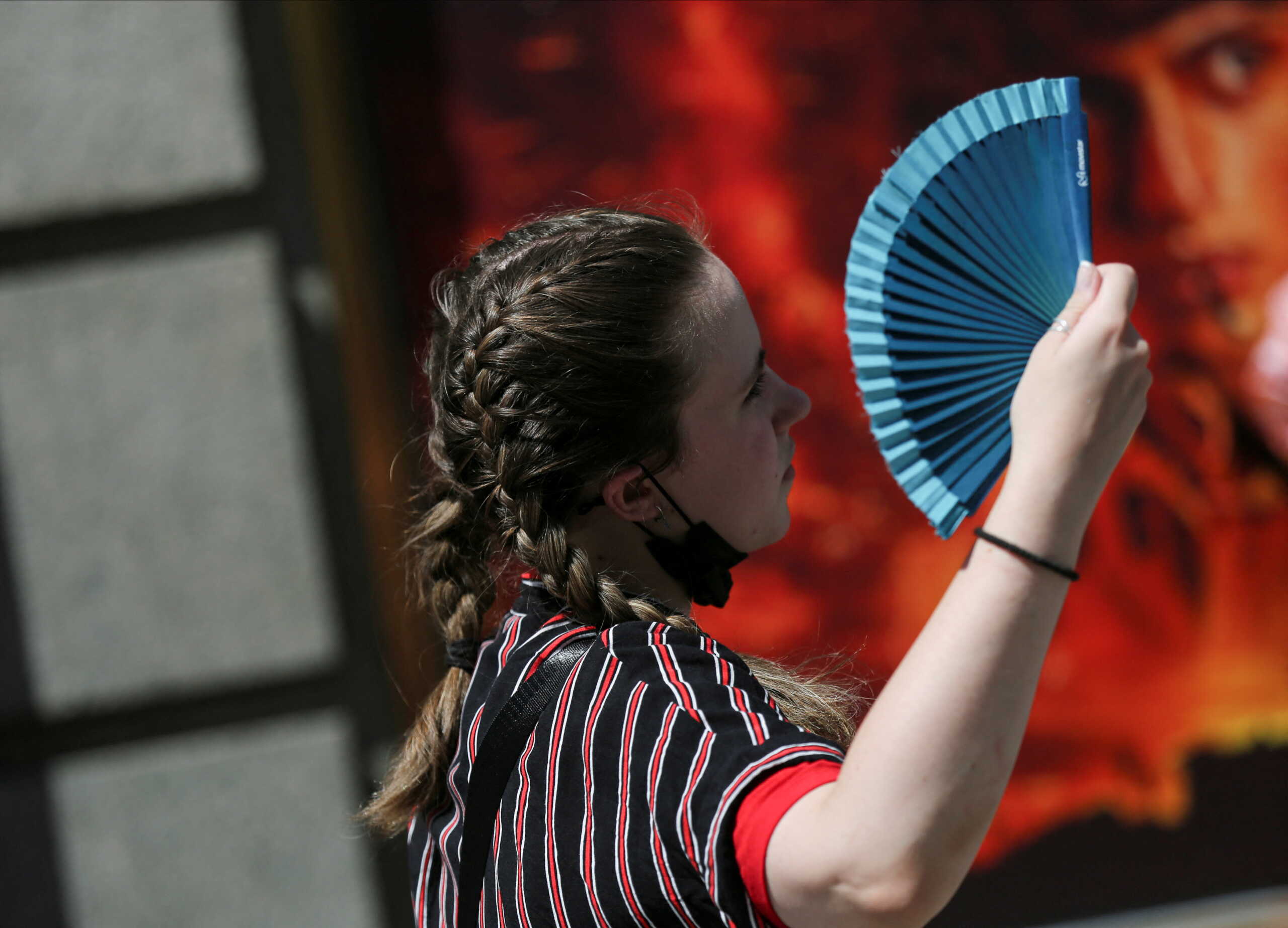 A woman uses a fan as she walks, during the second heatwave of the year, in Madrid, Spain, July 20, 2022. REUTERS