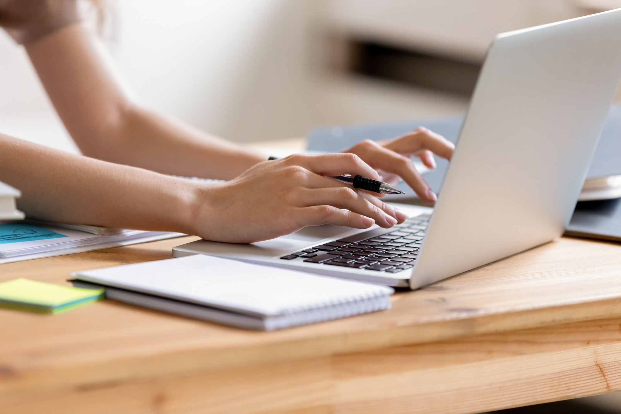 Cropped close up image woman hands holding pen typing on laptop student do homework prepare essay make research, businesswoman communicate online with client solve business questions distantly concept