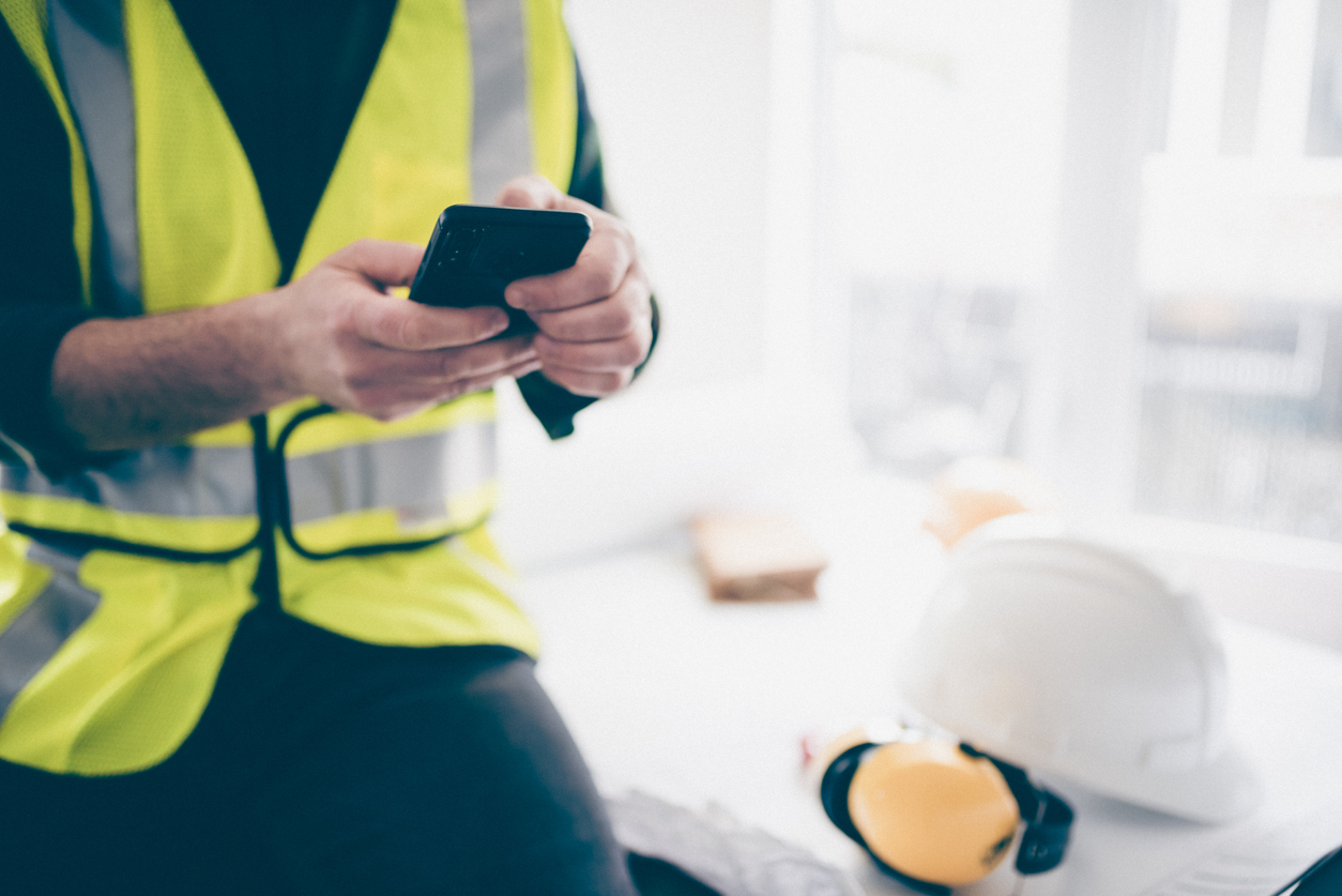 Building contractor using his phone to schedule the construction work