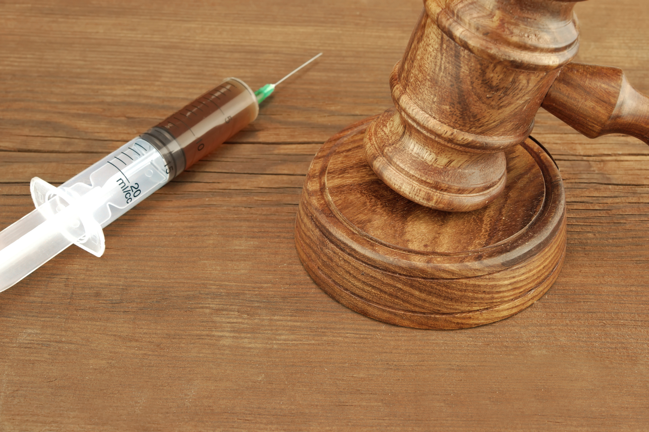 Close-up Of Judges Gavel And Syringe  With Injection On The Brown Wood Rough Background