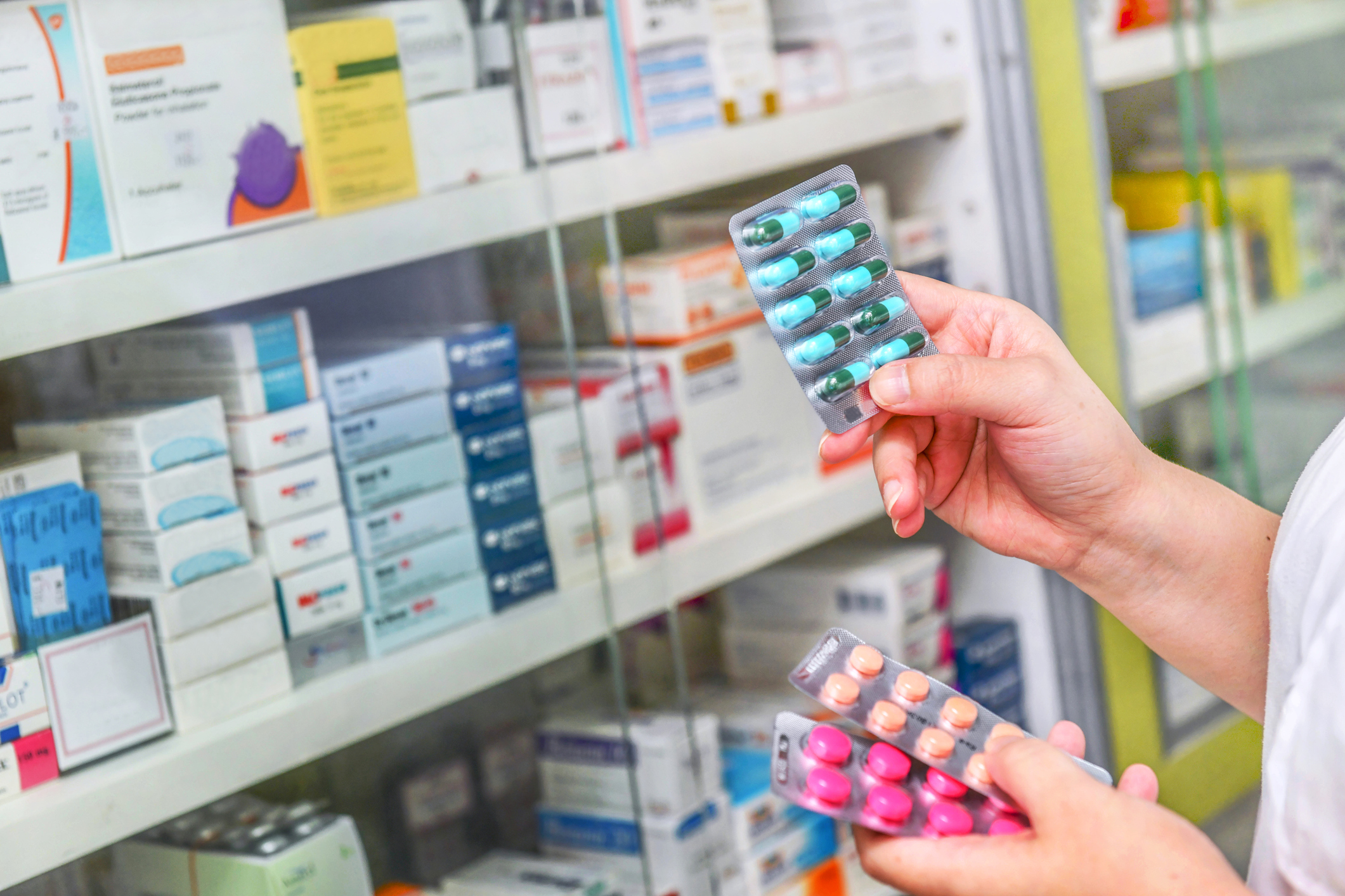 Hand holding medicine capsule pack at the pharmacy drugstore.
