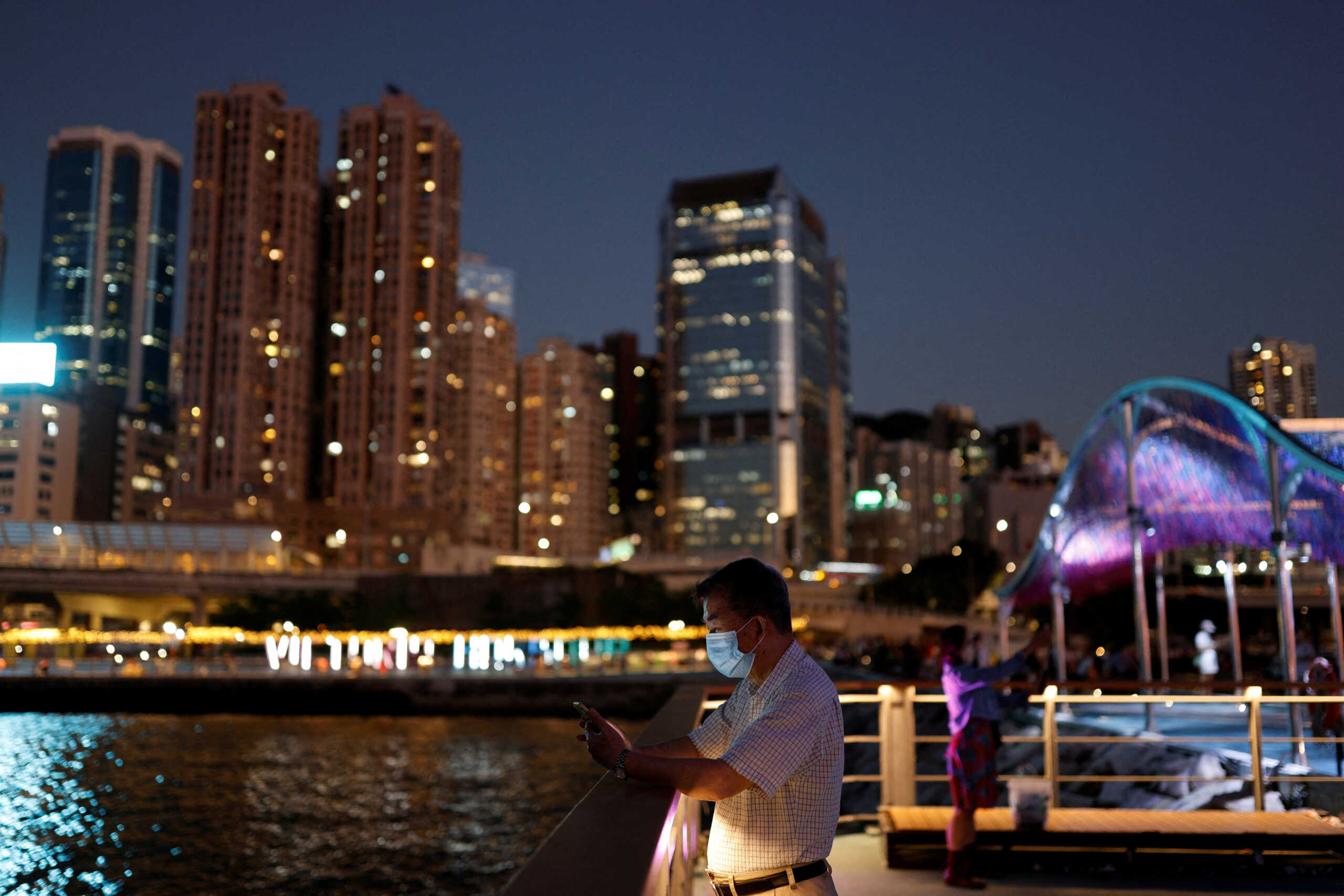 FILE PHOTO: A man checks his phone at a promenade during sunset in Hong Kong, China October 12, 2022. REUTERS