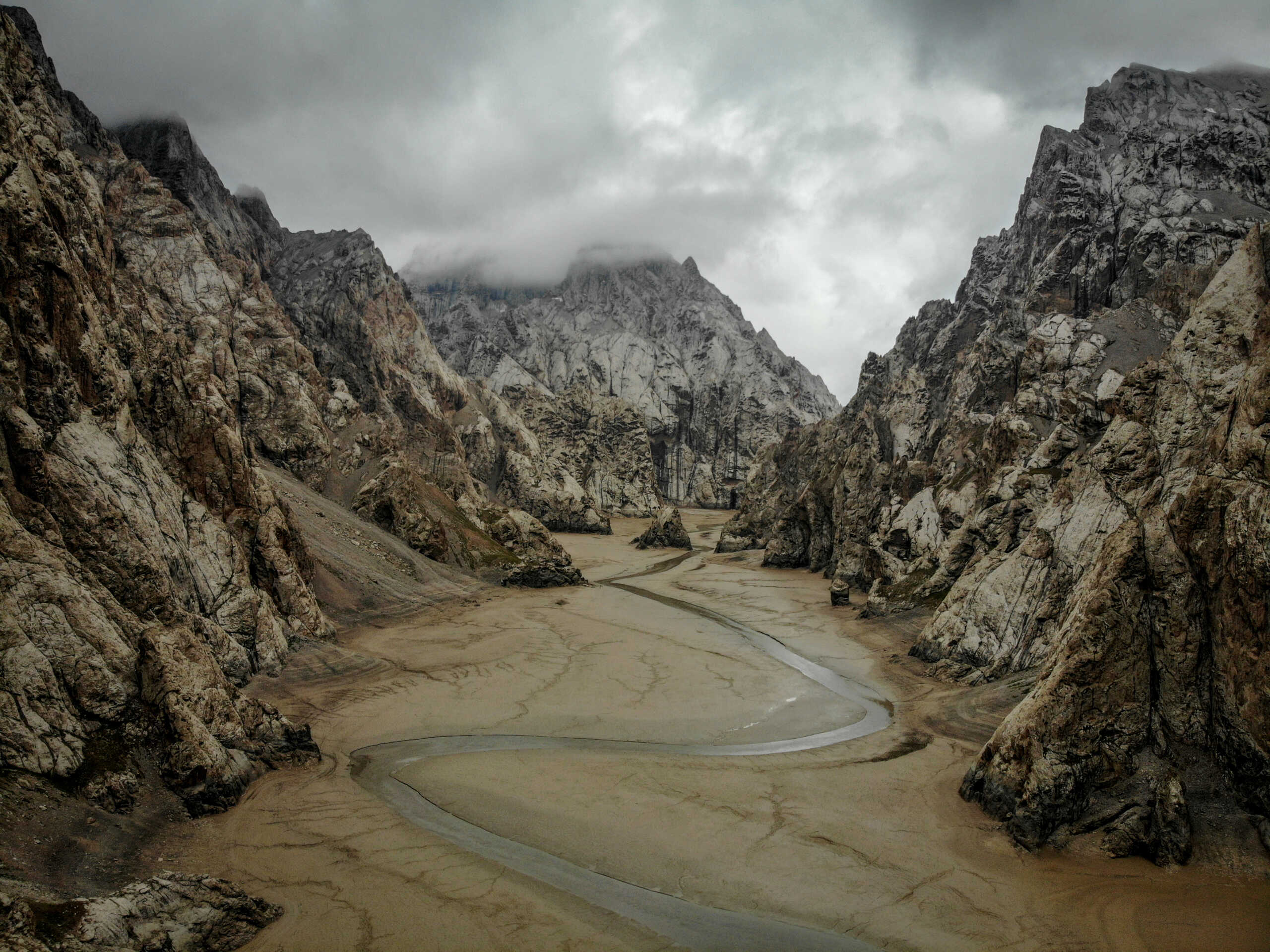 A small glacial stream creeps across Kok Suu’s muddy lake bed after a dry winter in Kyrgyzstan, August 9, 2018. Thomson Reuters Foundation