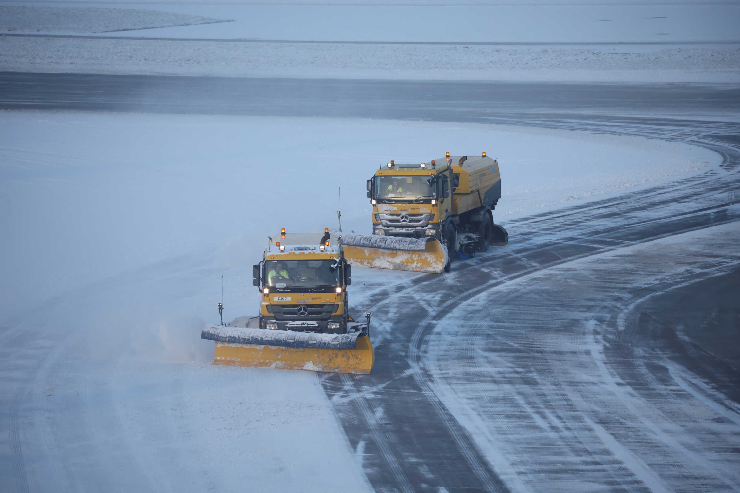 Snow ploughs clear snow from the airfield after overnight snow forced the closure of Manchester airport, in Manchester, Britain, January 19, 2023. REUTERS