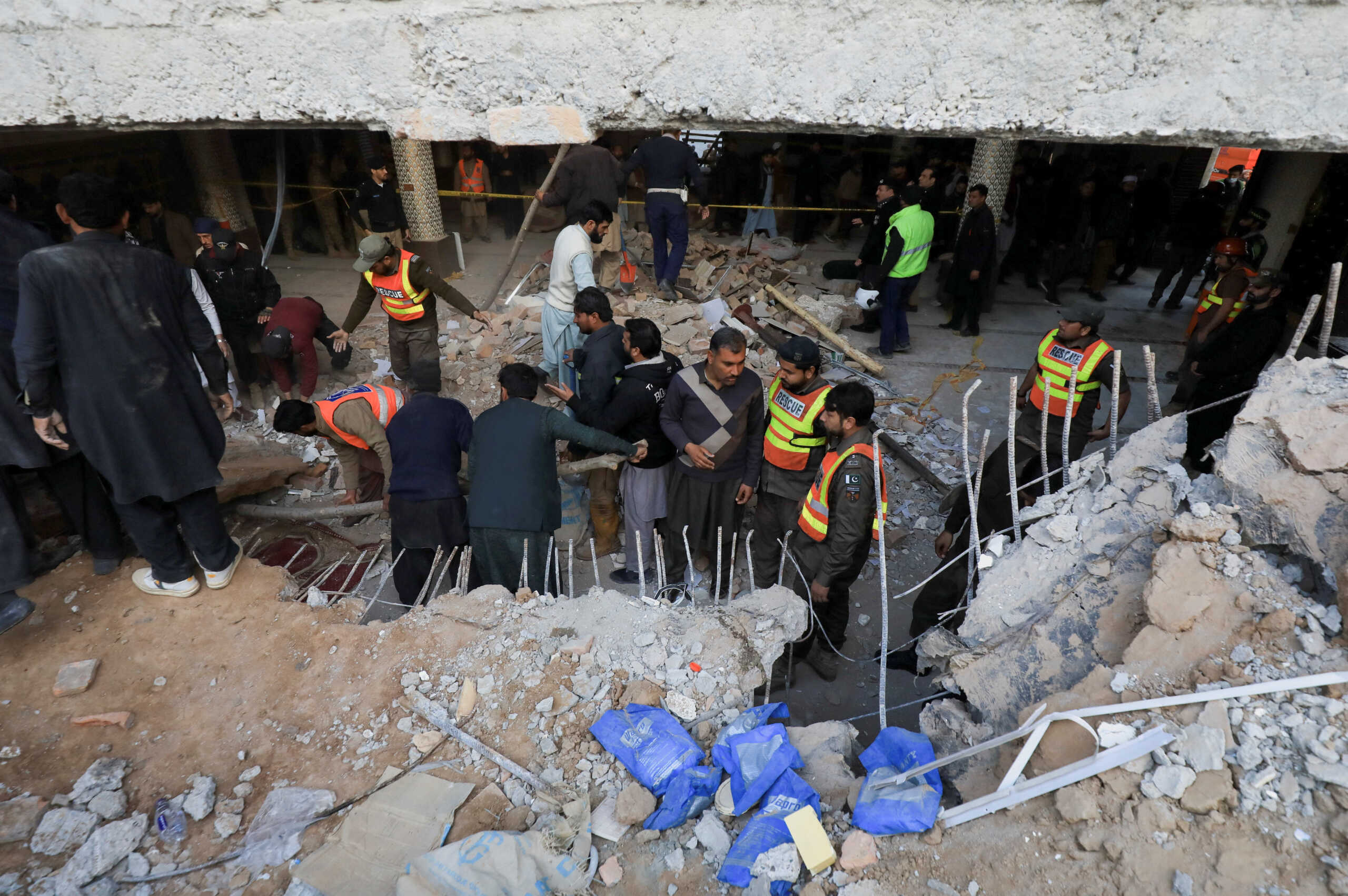 People and rescue workers look for survivors amid damages, after a suicide blast in a mosque in Peshawar, Pakistan January 30, 2023. REUTERS